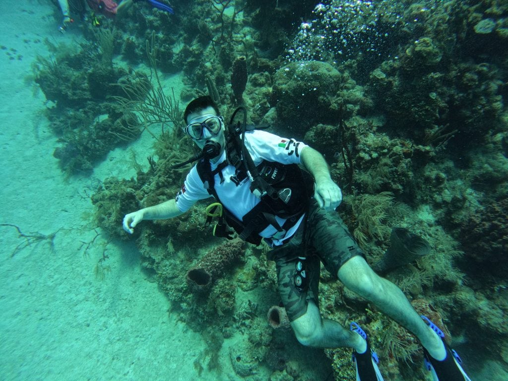 Scuba diver swimming over a coral formation in Utila, Honduras.