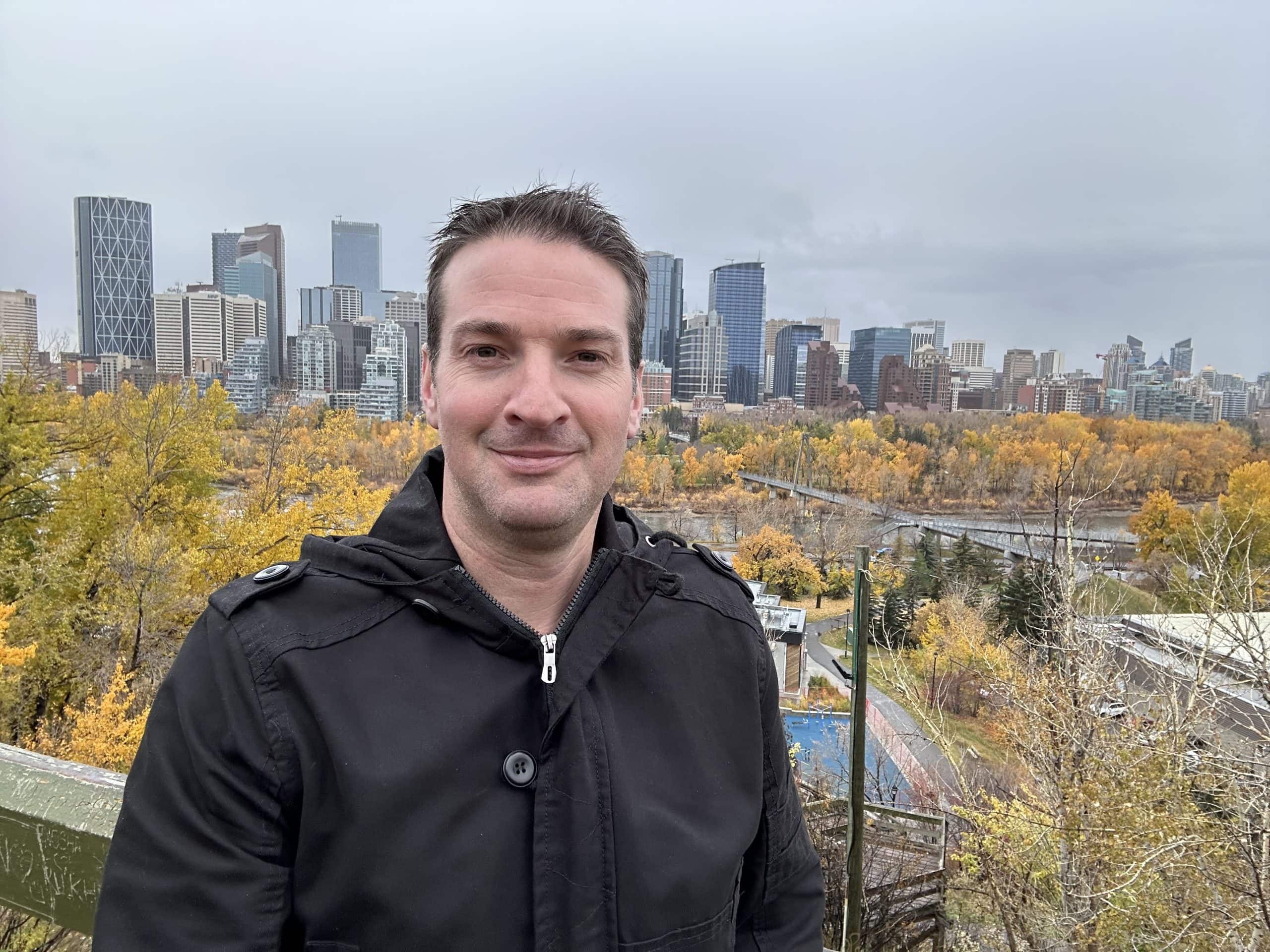 Ryan Gillard with the Calgary skyline in autumn, highlighting the city’s vibrant energy and natural surroundings.