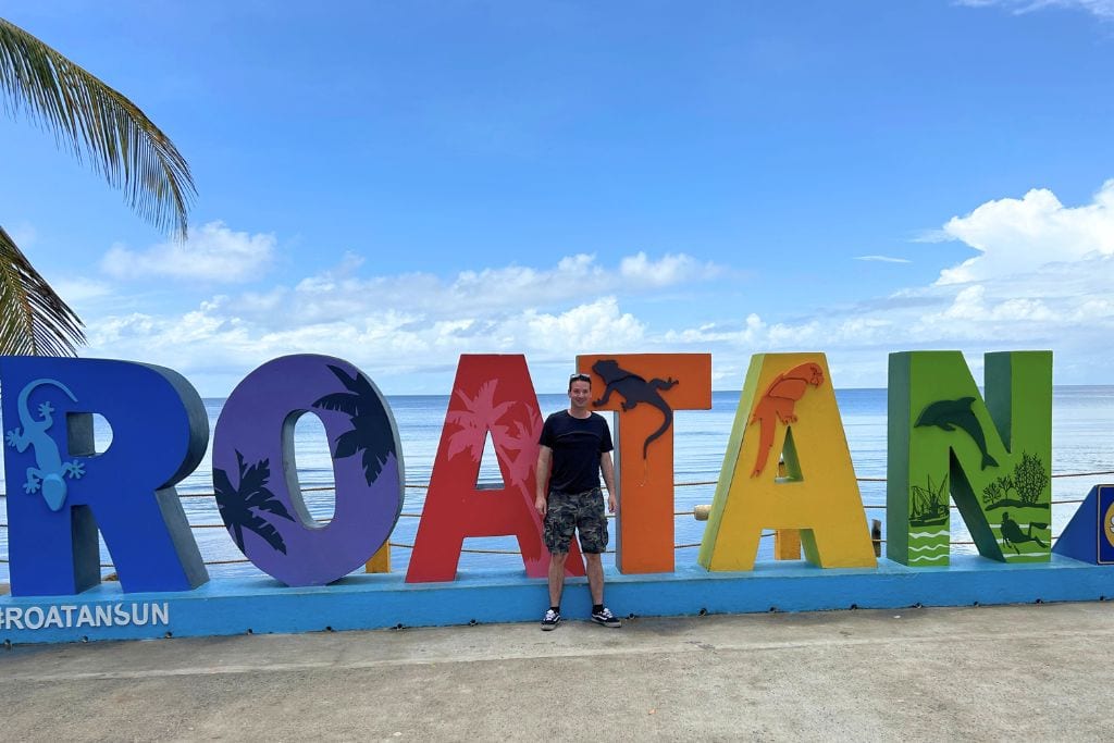 Colorful view of West End Roatan sign with palm trees and turquoise Caribbean waters, a popular tourist destination in Honduras