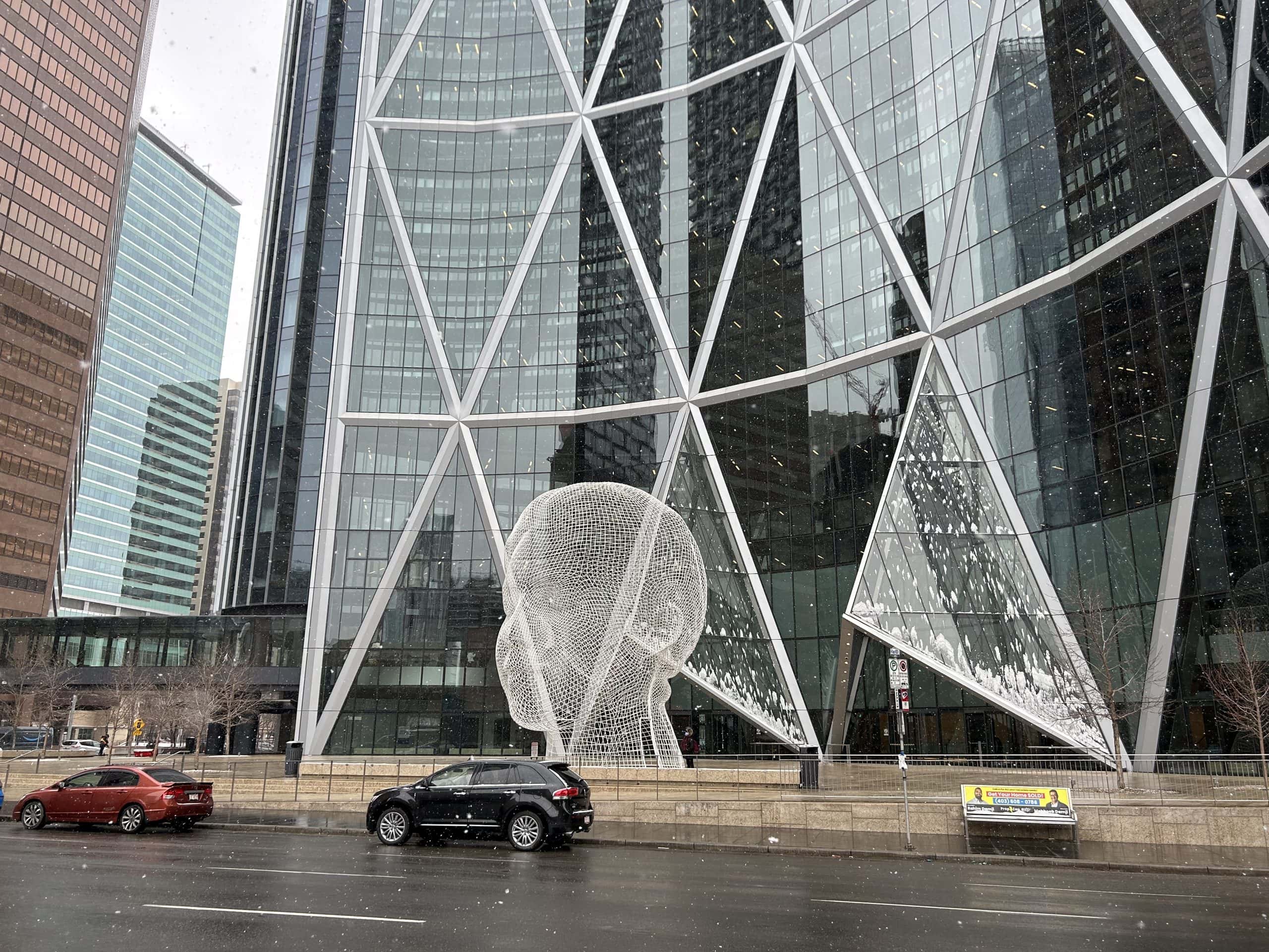Side profile of the Bow building with reflections and urban streetscape.
