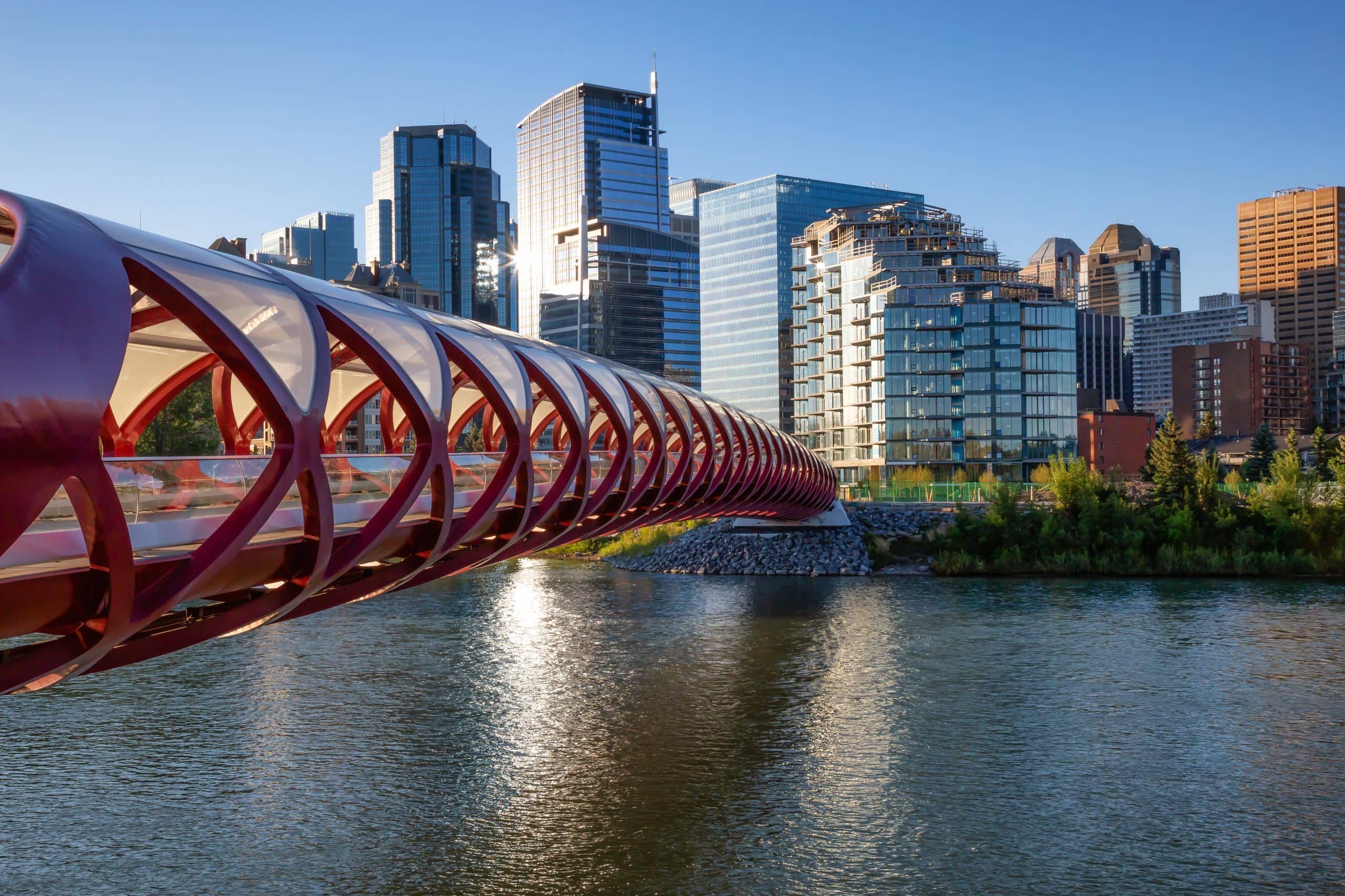 The iconic red Peace Bridge over the Bow River on a sunny summer day.