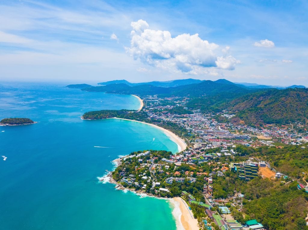 Aerial view of Patong beach with blue turquoise seawater, mountain hills, and tropical green forest trees with Andaman sea in Phuket island in summer, Thailand in travel trip. Nature background.