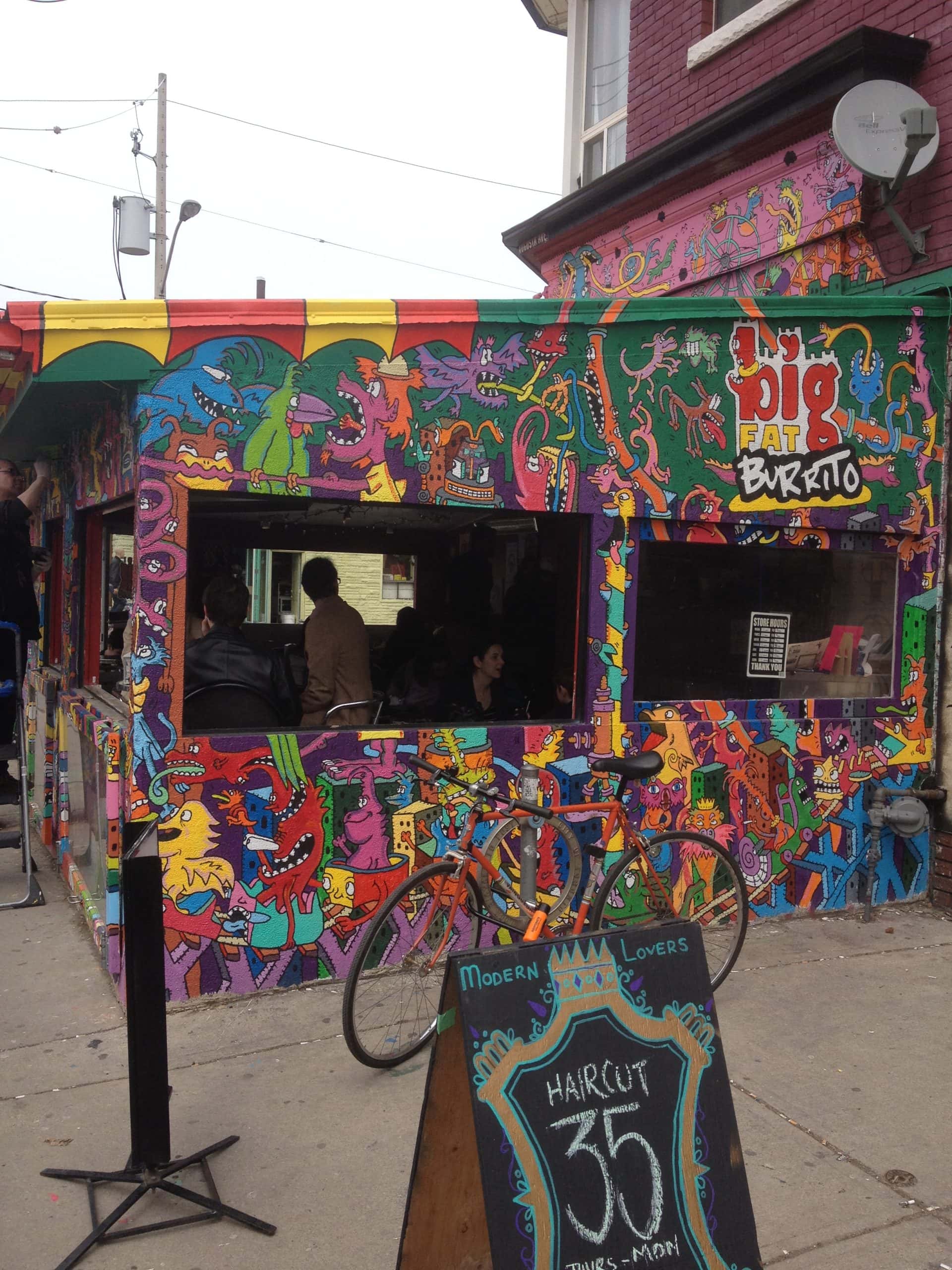 vibrant street scene in Kensington Market filled with murals and eclectic shops