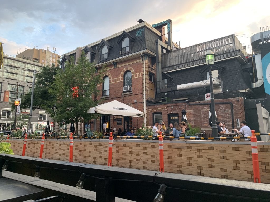 People eating lunch across the street from the Drake Hotel on a hot summer day.
