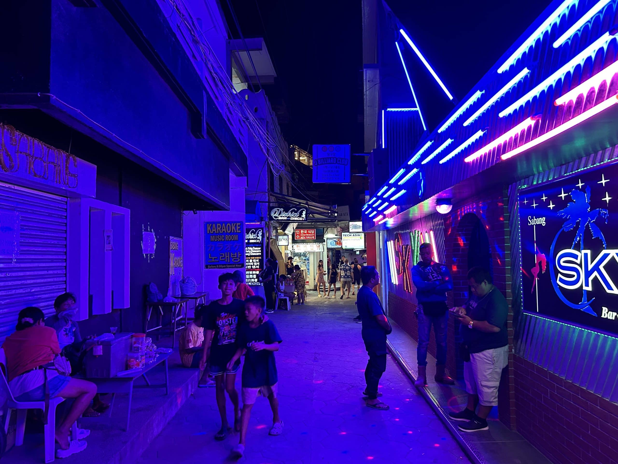 colourful neon-lit alley in Sabang, Puerto Galera at night with bars, clubs, and people enjoying the vibrant nightlife scene