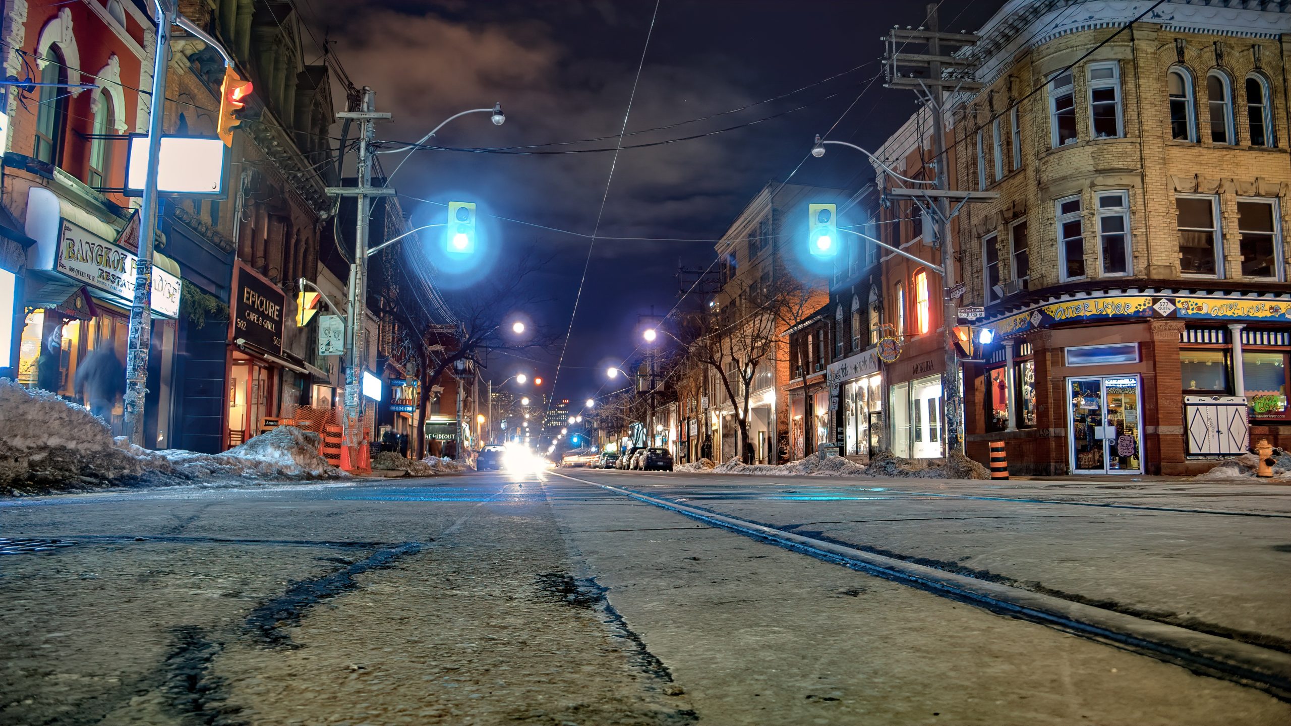 bustling Queen St W in Toronto lined with trendy shops, cafes, and streetcar tracks