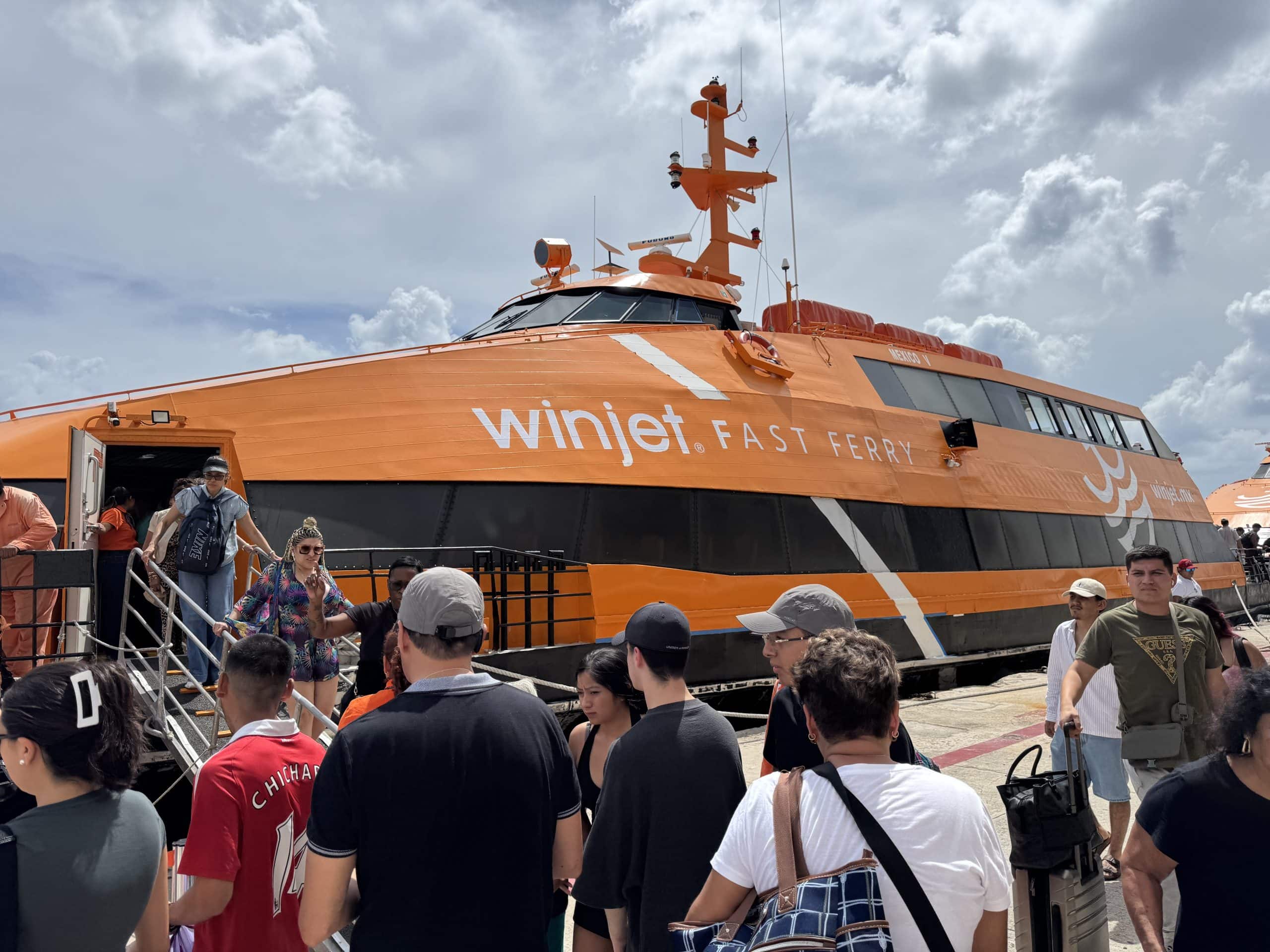 Travellers board the bright orange Winjet fast ferry in Playa del Carmen for the short ride to Cozumel, a common route for visitors arriving from Cancun.