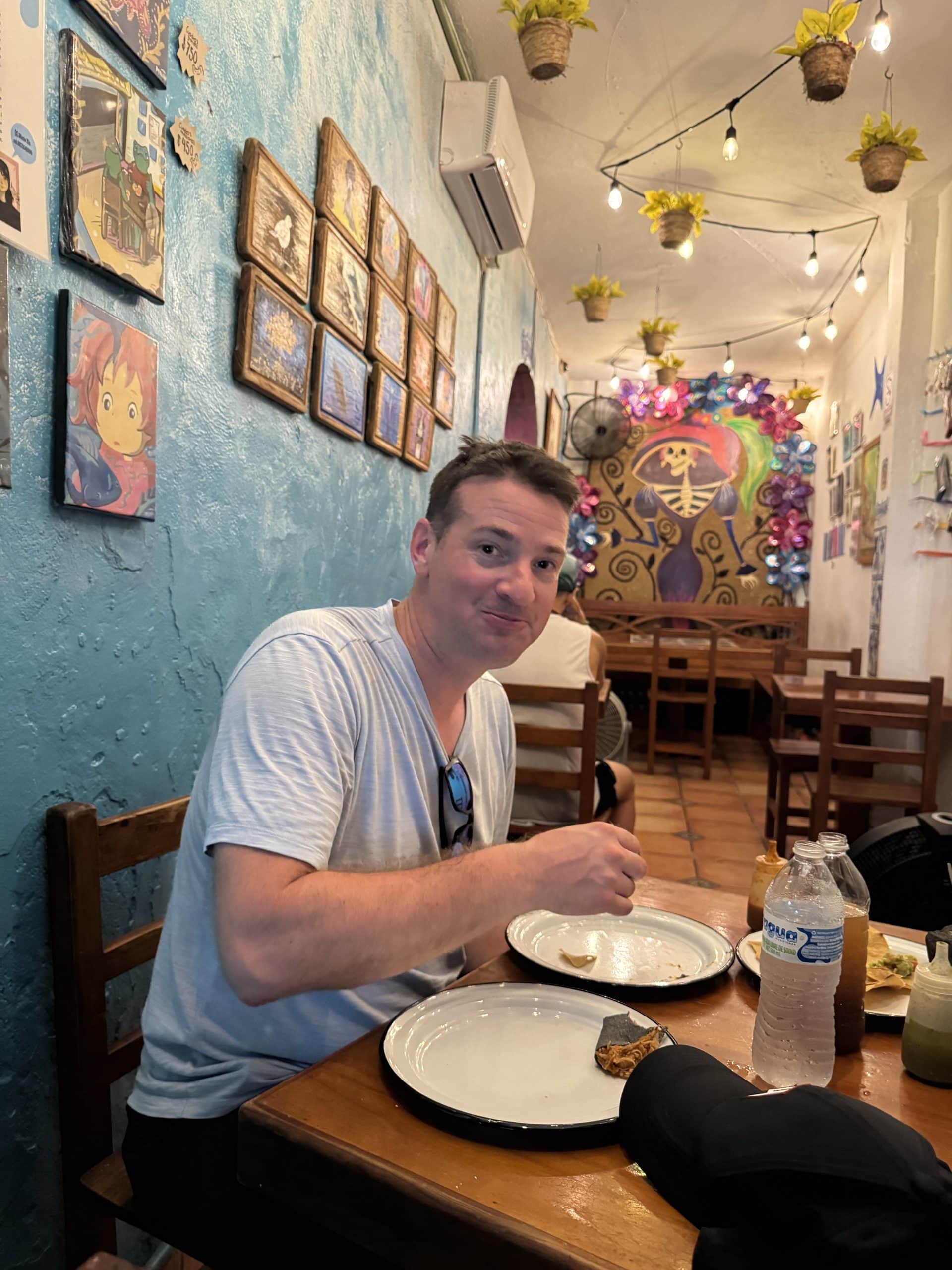 Enjoying authentic Mexican tacos at a colourful local restaurant in downtown Cozumel, surrounded by vibrant art and cozy decor.