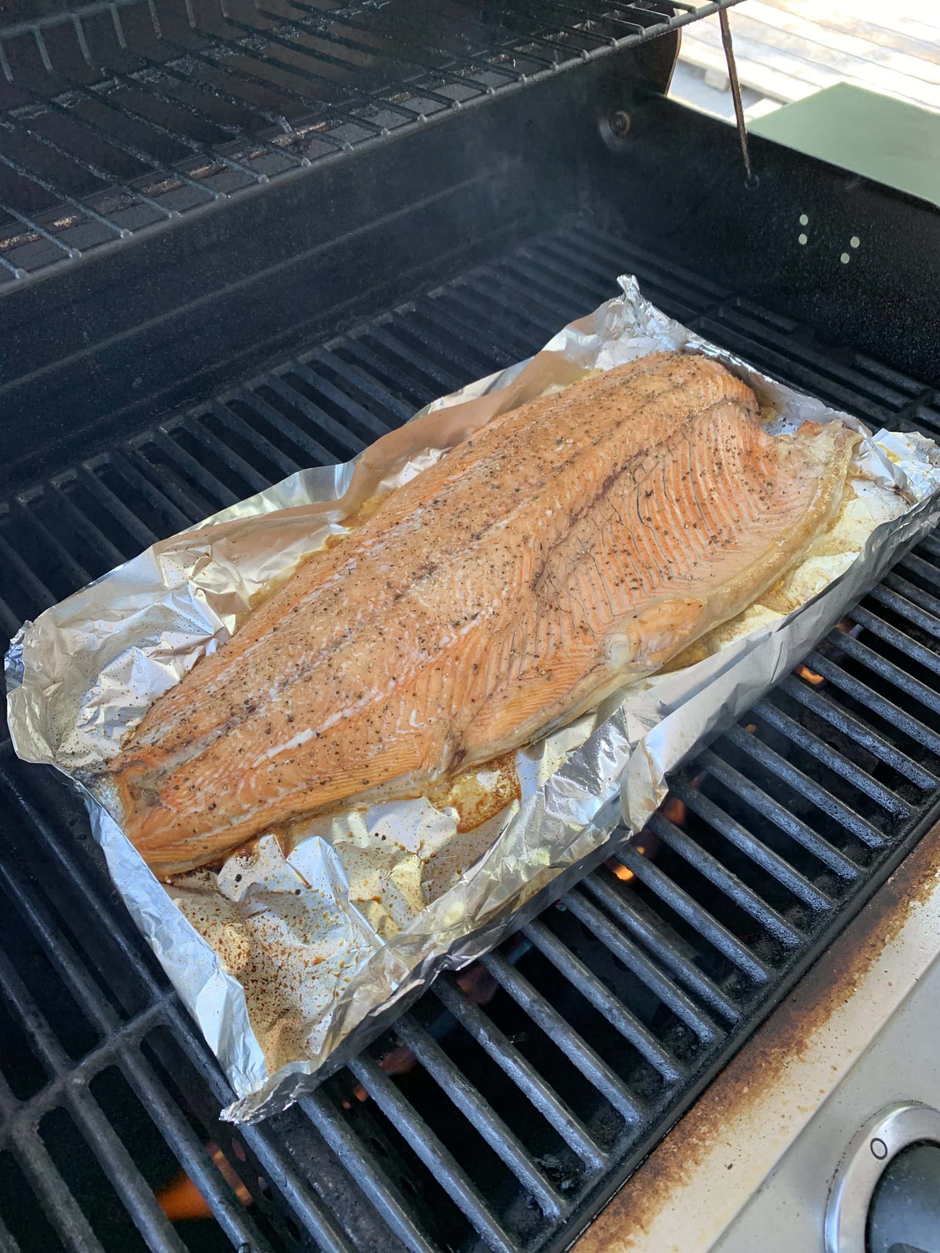 Freshly caught salmon fillet seasoned and grilling on a barbecue over foil in Port Renfrew, BC.