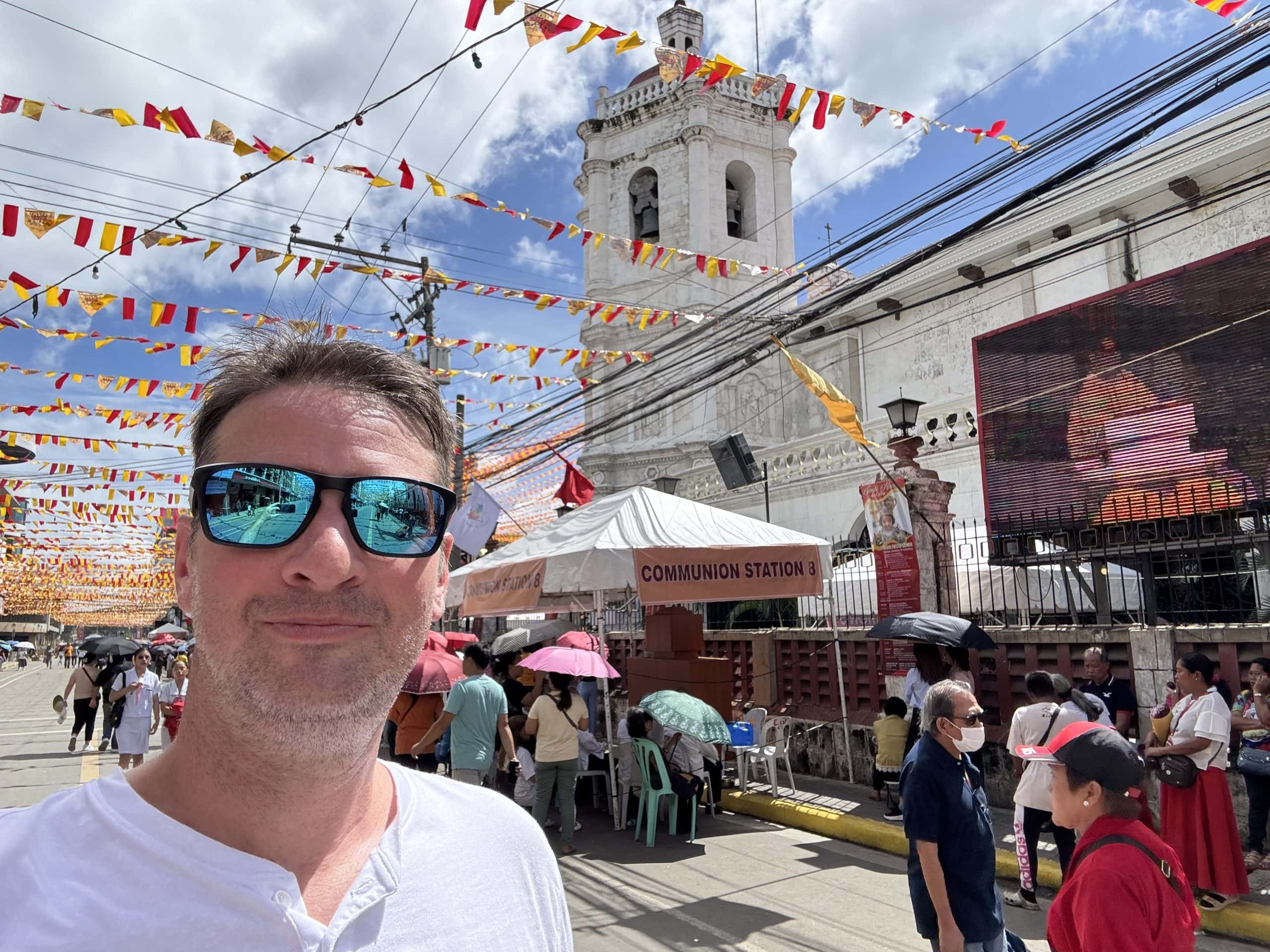 Celebrating Sinulog in Cebu City with vibrant street decorations, local crowds, and the historic Basilica del Santo Niño in the background.
