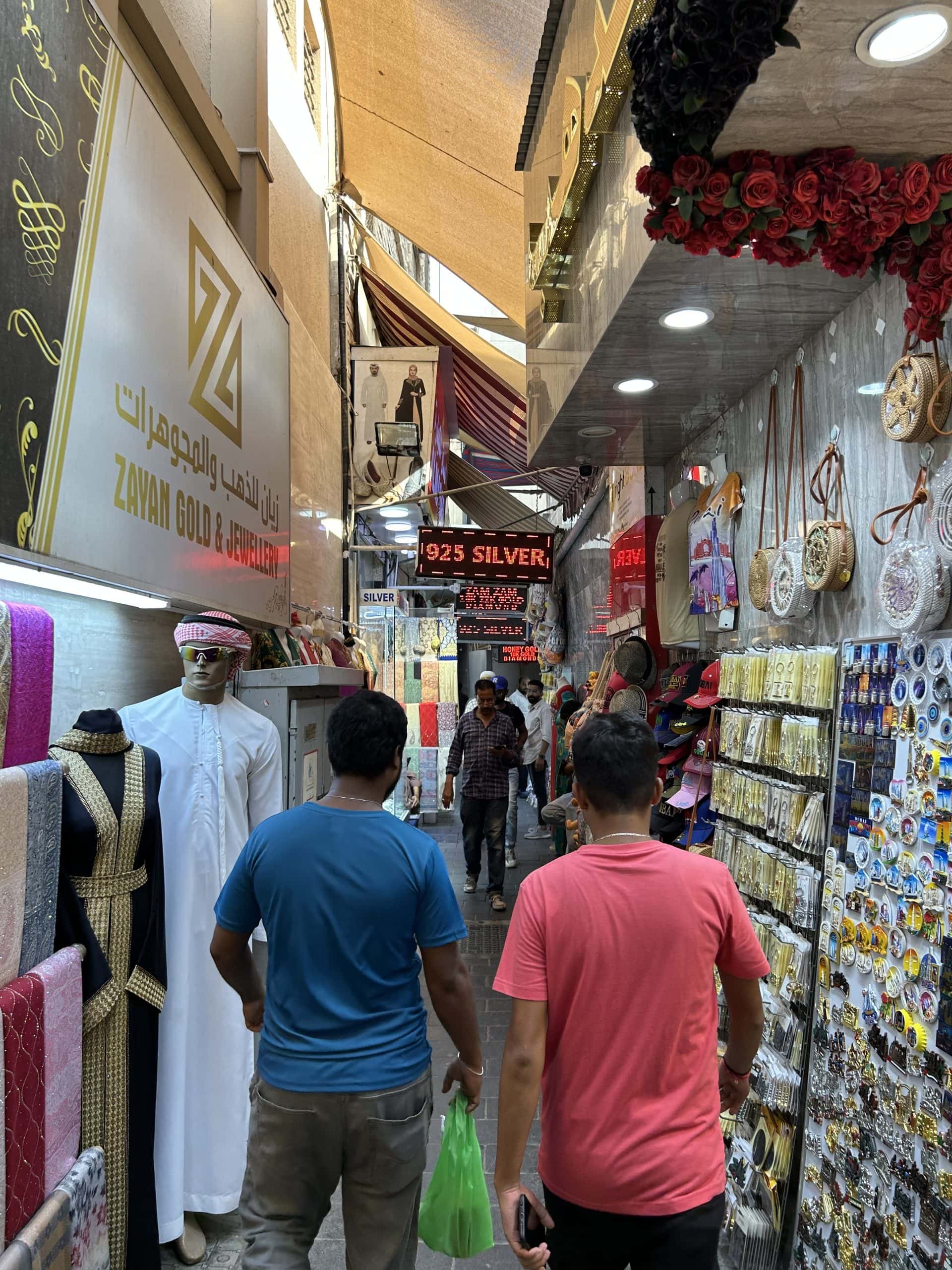 Bustling alley in Dubai’s Gold Souk with shops selling jewelry, textiles, souvenirs, and traditional clothing, showcasing the vibrant atmosphere of the city’s famous market.