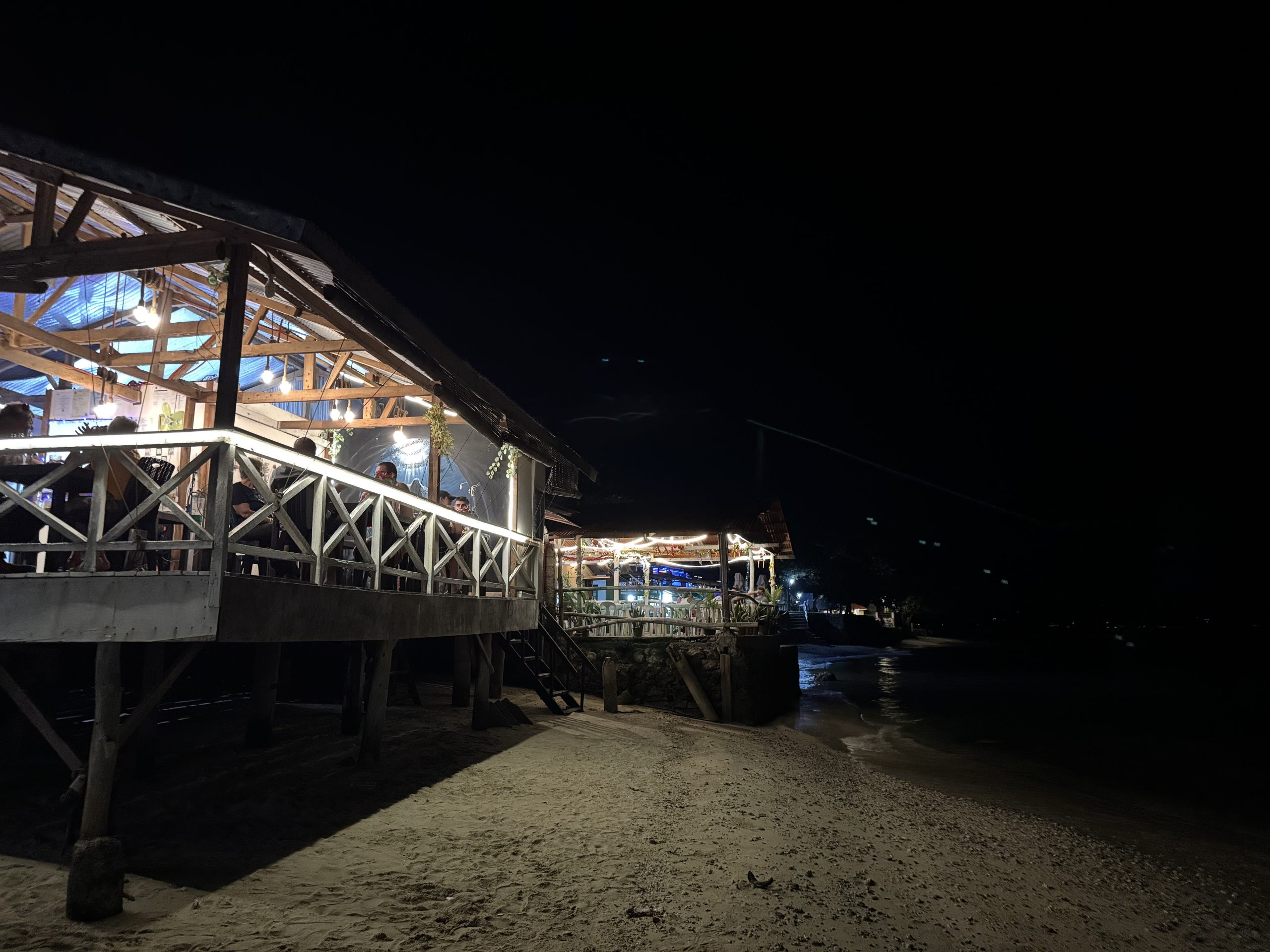 Beachfront restaurants in Moalboal glow with warm lights at night, offering relaxed seaside dining right above the sand along Panagsama Beach.