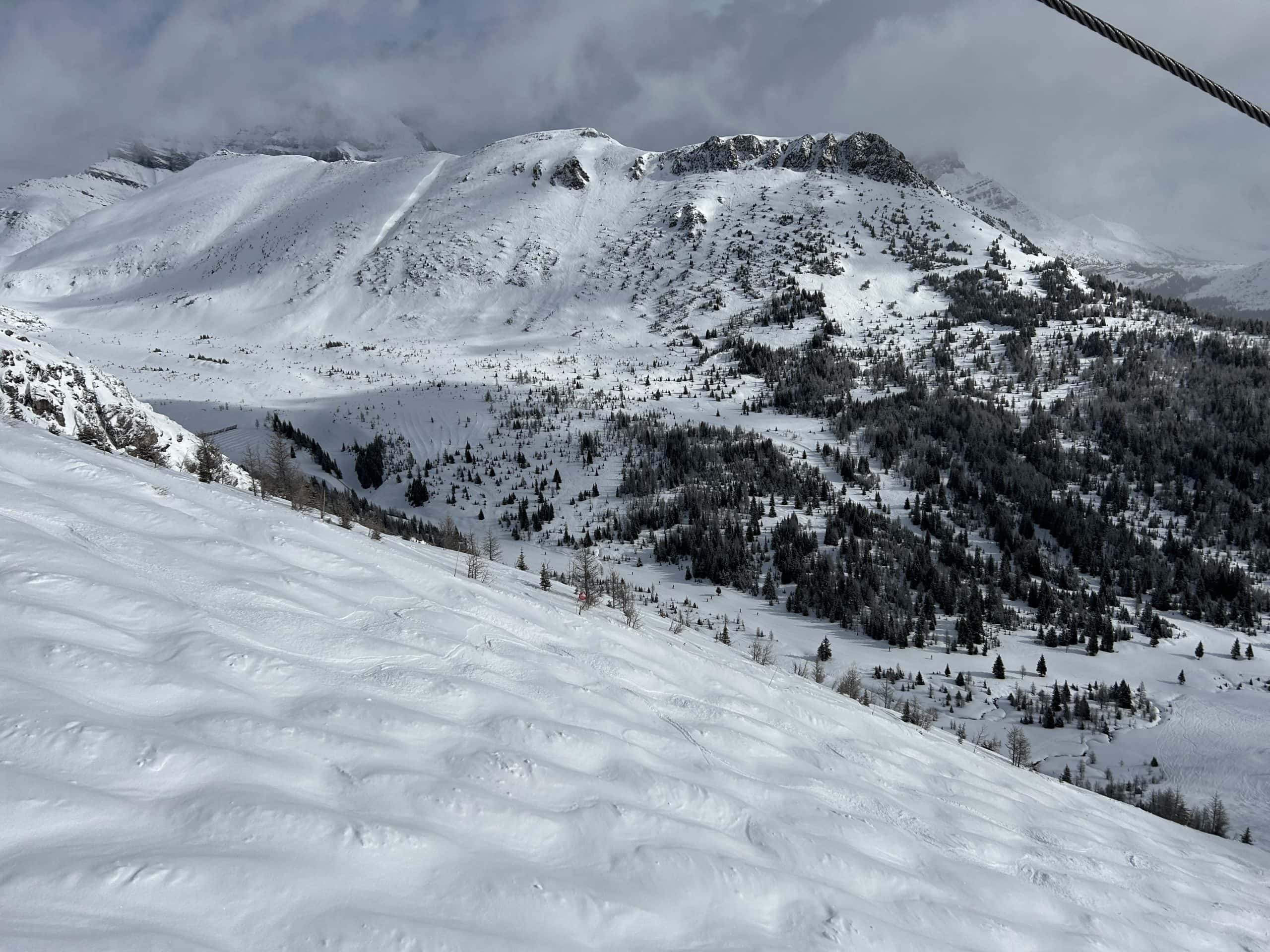 Snow blankets the rugged peaks and tree-filled valleys of Lake Louise, creating a breathtaking alpine winter scene perfect for skiing and mountain adventures.