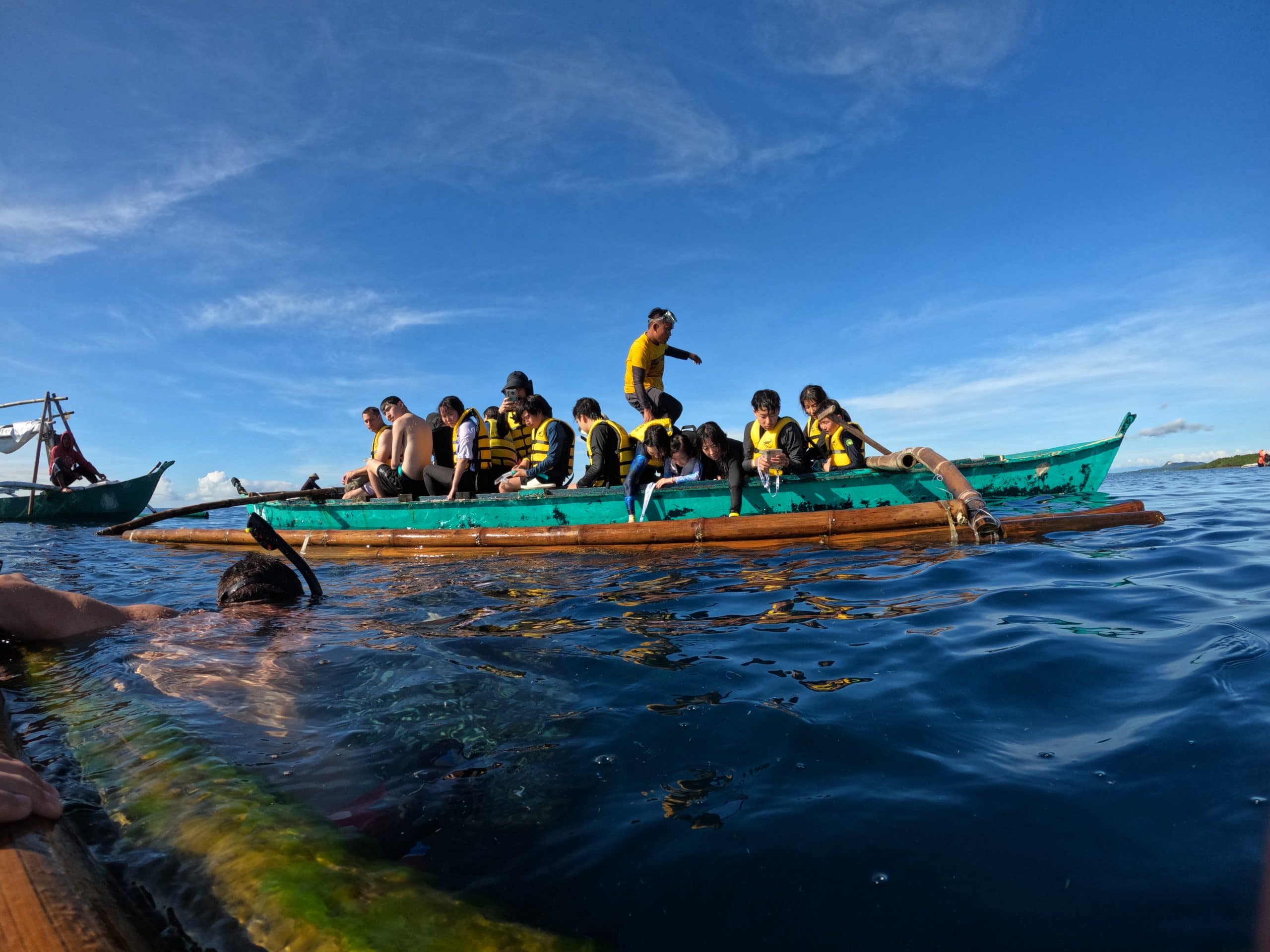 Snorkellers and guides preparing to enter the water from a crowded outrigger boat during the Lila whale shark tour in Bohol.