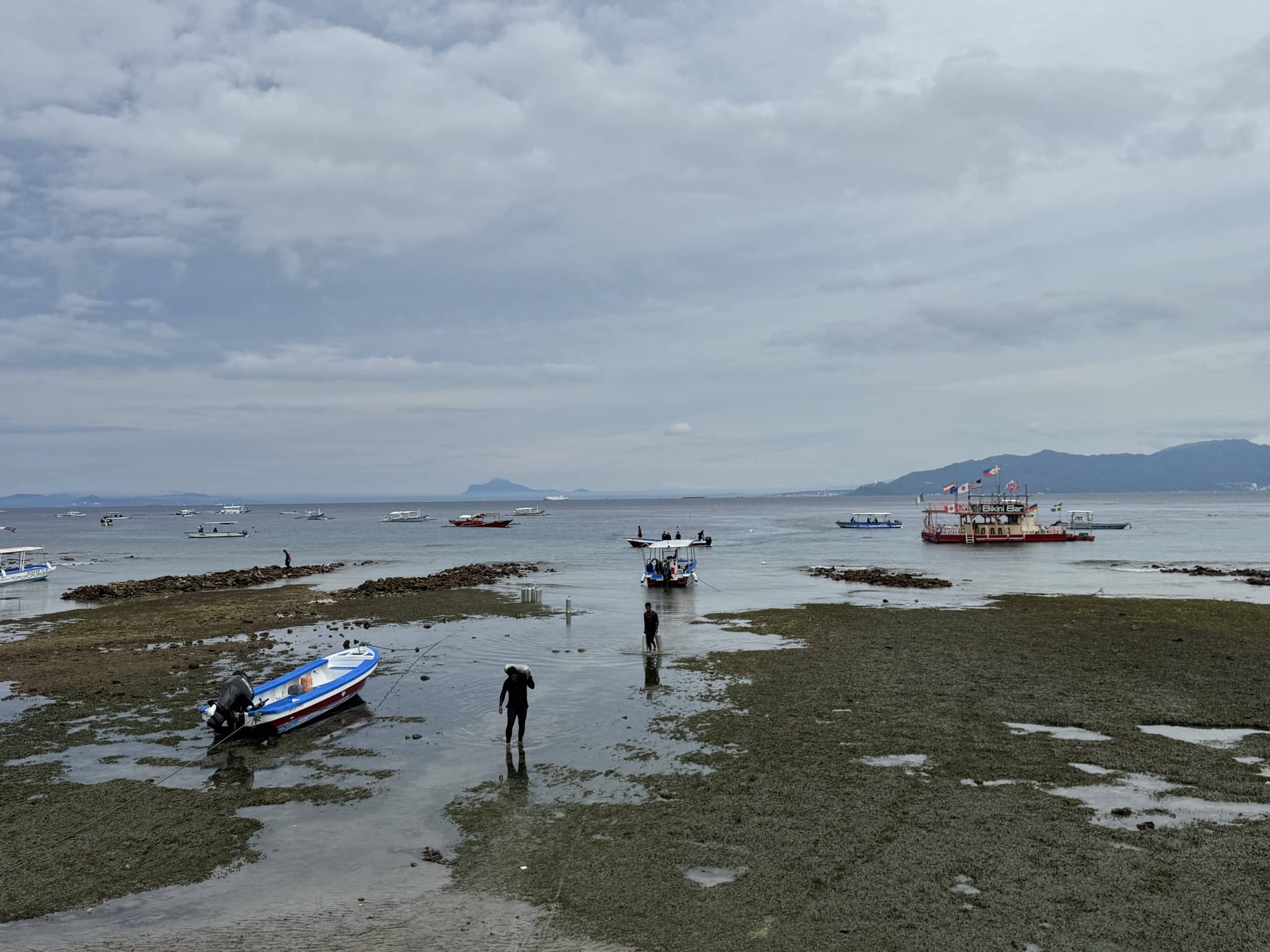 Walking out to dive boats in Sabang, Puerto Galera during low tide before short boat rides to nearby reefs.