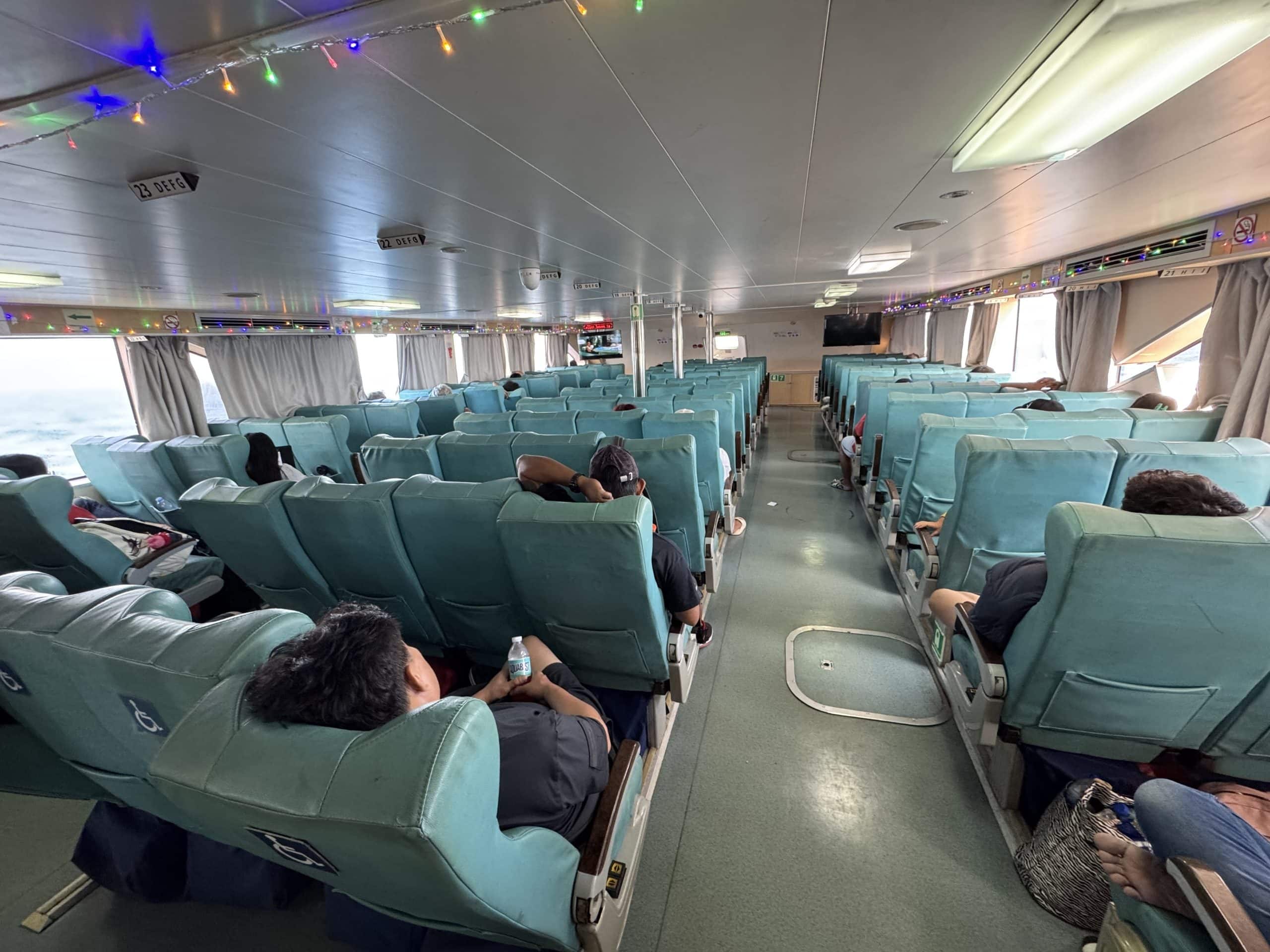 Interior of the fast ferry from Batangas to Puerto Galera showing spacious seating, air conditioned cabin, and passengers relaxing during the one hour crossing.