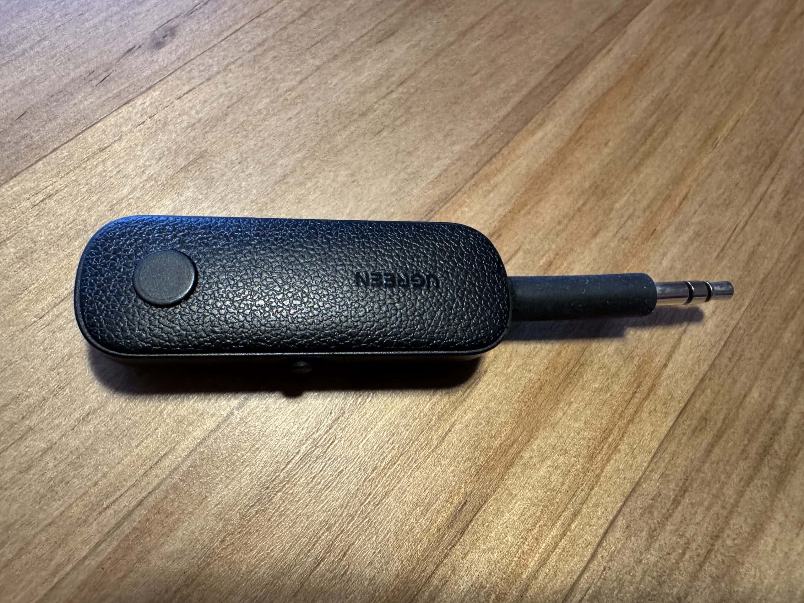 Bluetooth audio transmitter plugged into an airplane headphone jack to use wireless headphones for in flight entertainment.