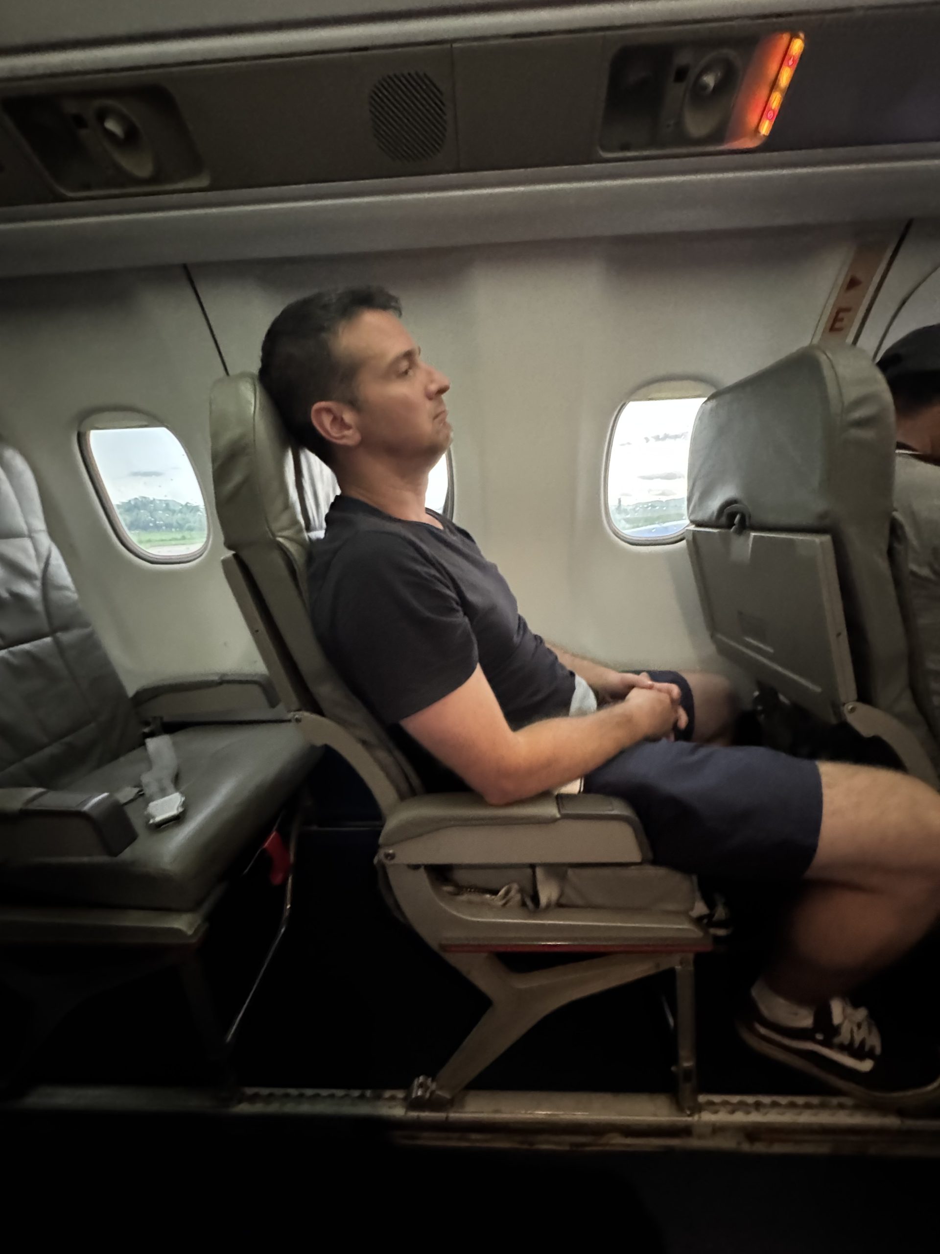 Passenger resting in an economy seat on a small regional airplane during a long travel day.