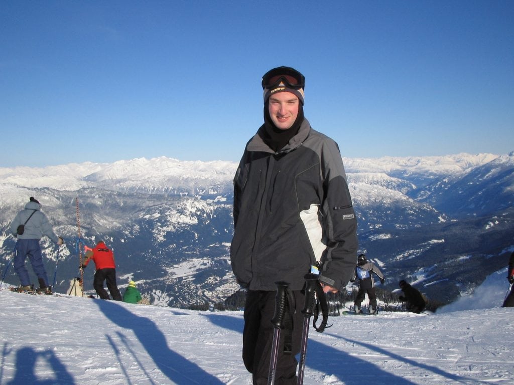 Skier at the summit of Whistler Mountain with panoramic views of the snow covered Coast Mountains and alpine terrain in Whistler, British Columbia