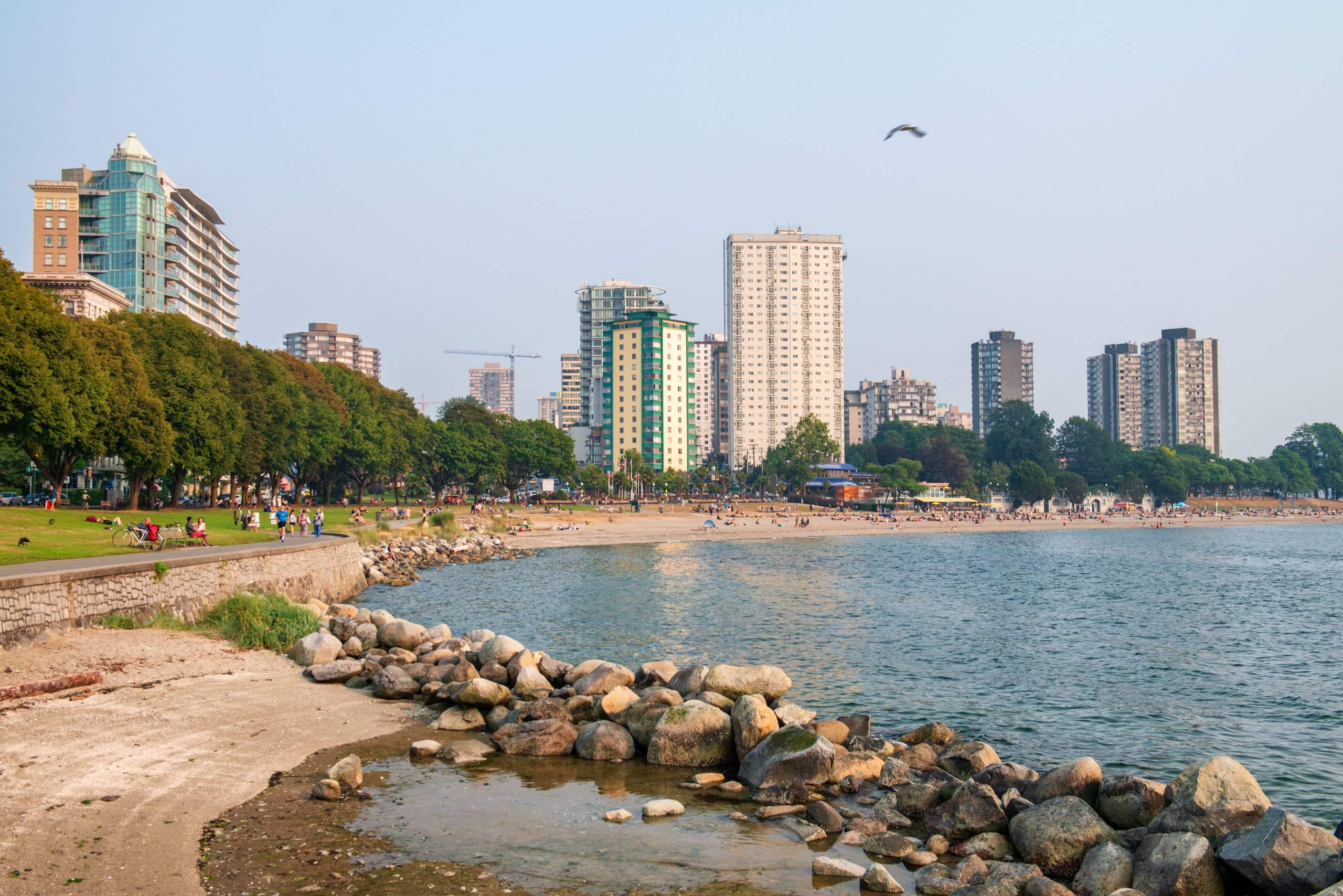 View of Vancouver’s West End skyline from Stanley Park with waterfront seawall, beach, and residential high rise buildings along English Bay