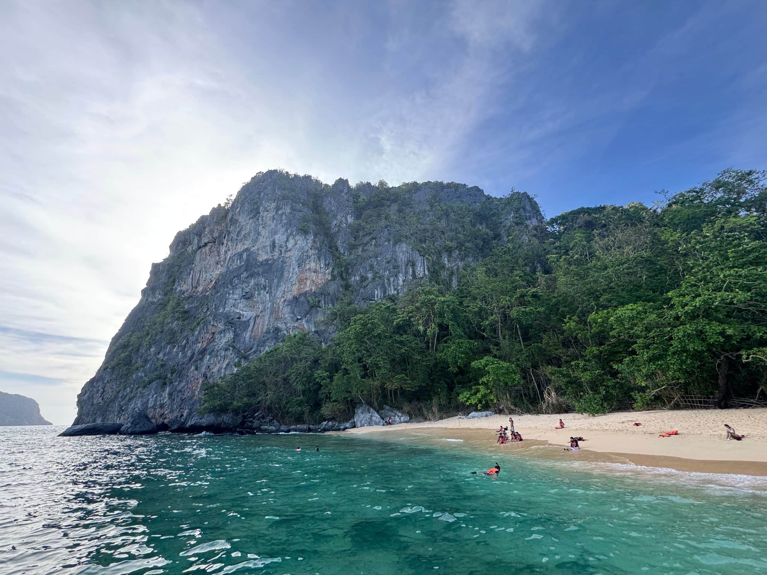 Helicopter Island in El Nido with white sand beach and turquoise water backed by towering limestone cliffs in Palawan Philippines