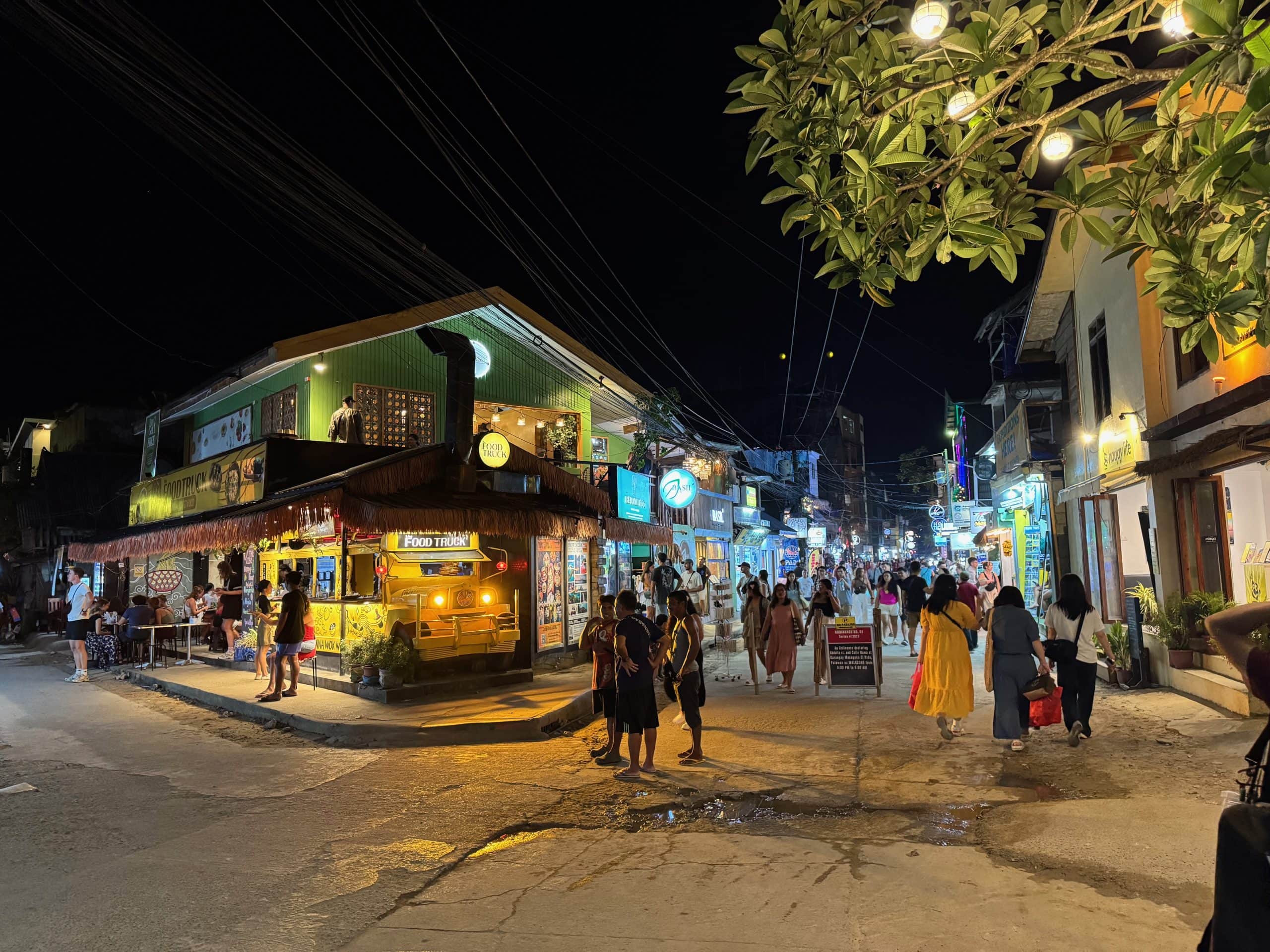 Busy El Nido nightlife street filled with restaurants, bars, and travellers enjoying the lively evening atmosphere in Palawan