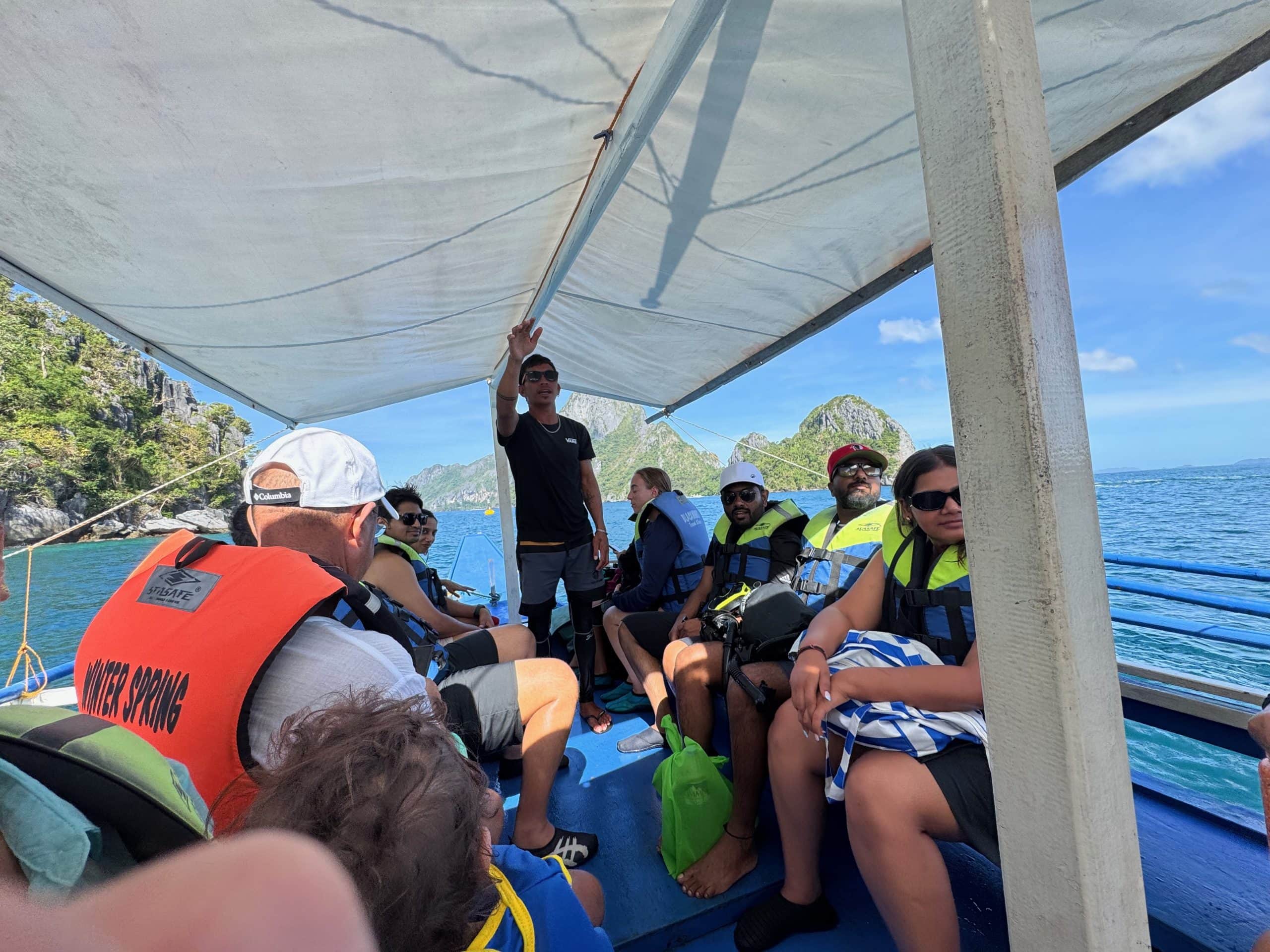 Group of travellers on a traditional boat during an El Nido island hopping tour, cruising past limestone islands in Palawan
