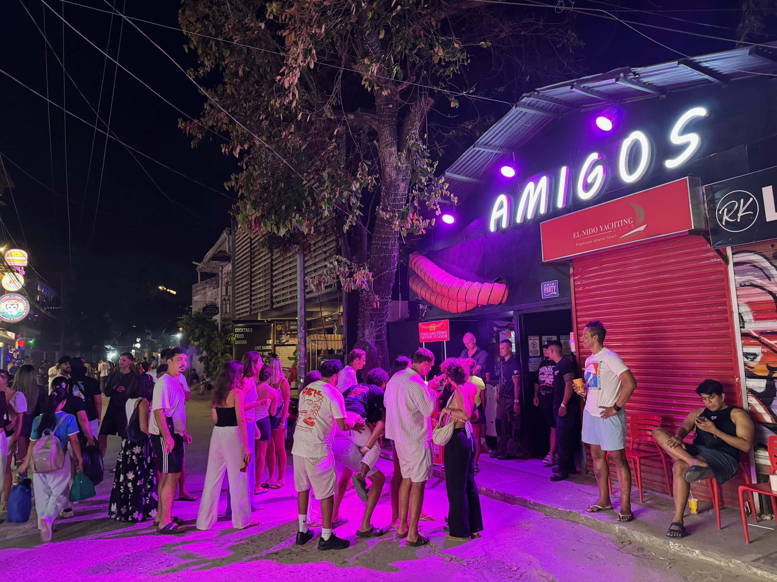 El Nido nightlife with tourists outside Amigo’s bar and lively street scene in Palawan Philippines