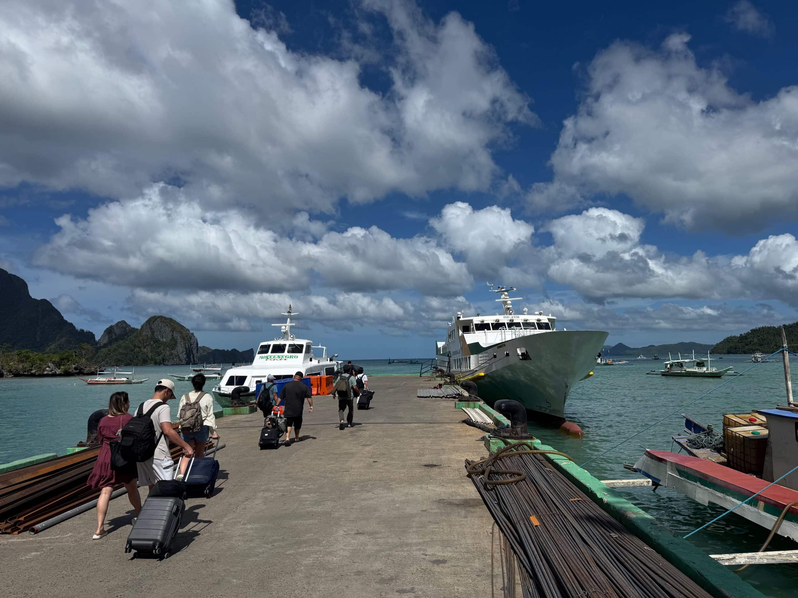 Travellers arriving at El Nido port with ferries and limestone islands in the background Palawan Philippines