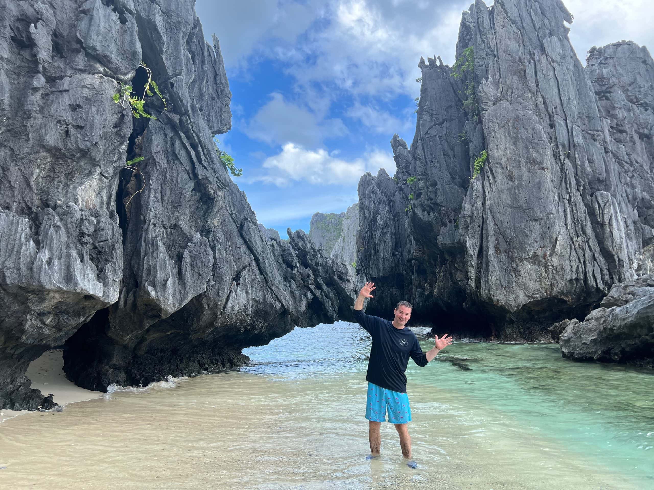 Traveller standing in turquoise water surrounded by limestone cliffs during Tour A in El Nido Palawan Philippines