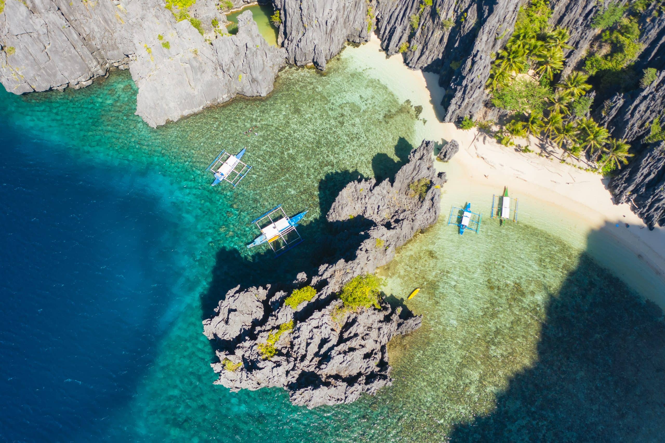 El Nido, Palawan, Philippines, aerial view of boats in lagoon and cliffs rocky mountains scenery at Secret Lagoon beach.