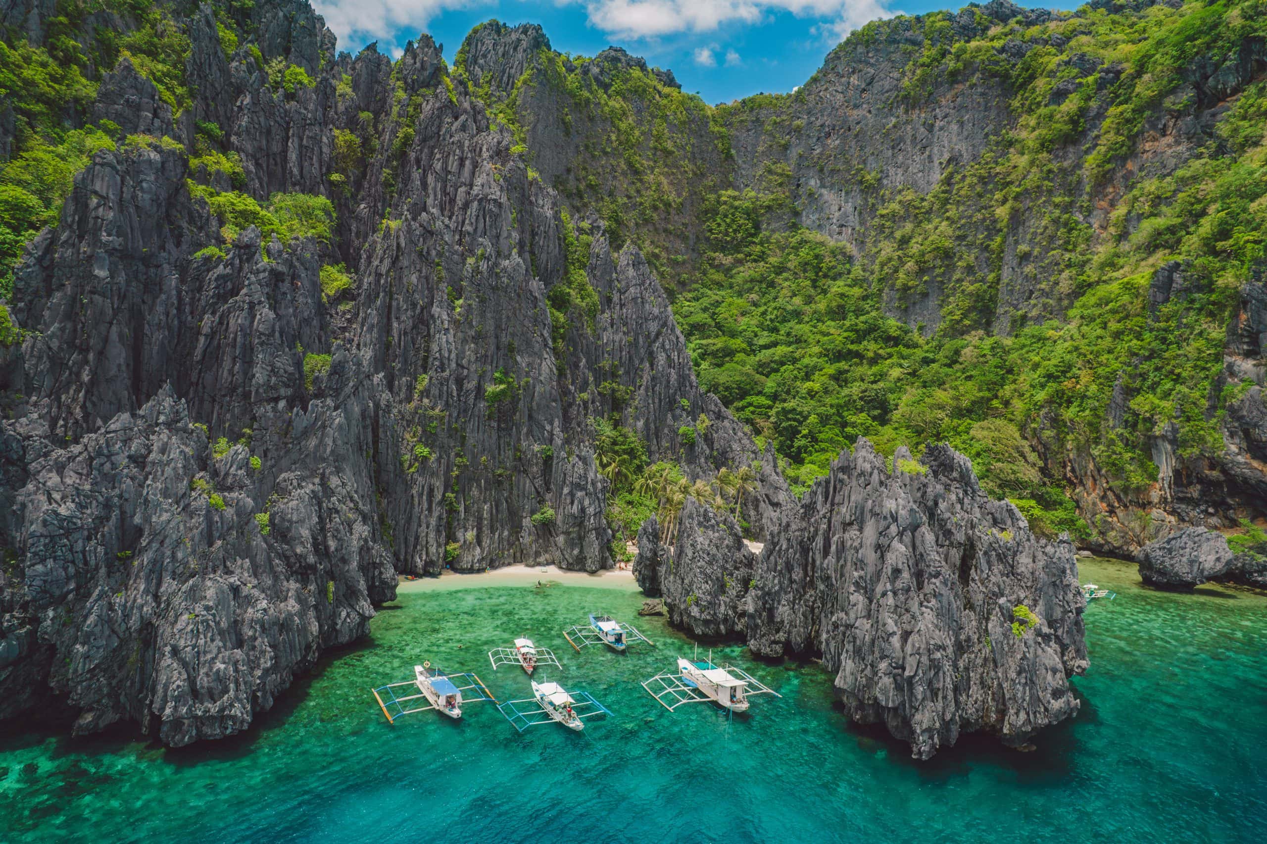 El Nido Palawan lagoon with limestone cliffs and boats in crystal clear turquoise water Philippines