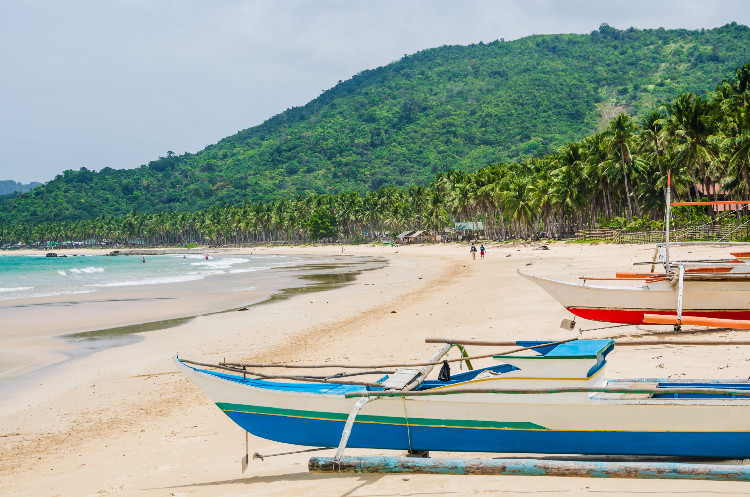 Local boats on Nacpan Beach on sunny day. El Nido, Palawan, Philippines