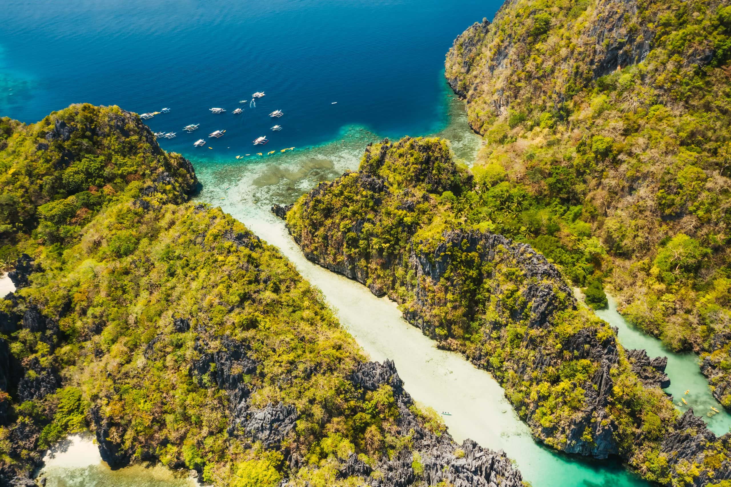 Palawan, Philippines aerial view of tropical Miniloc island. Tourism trip boats moored at entrance to big lagoon.