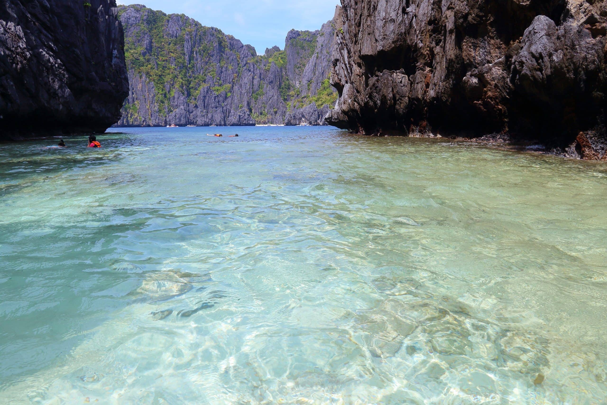 Crystal clear shallow water in El Nido surrounded by limestone cliffs and calm turquoise lagoon scenery in Palawan Philippines