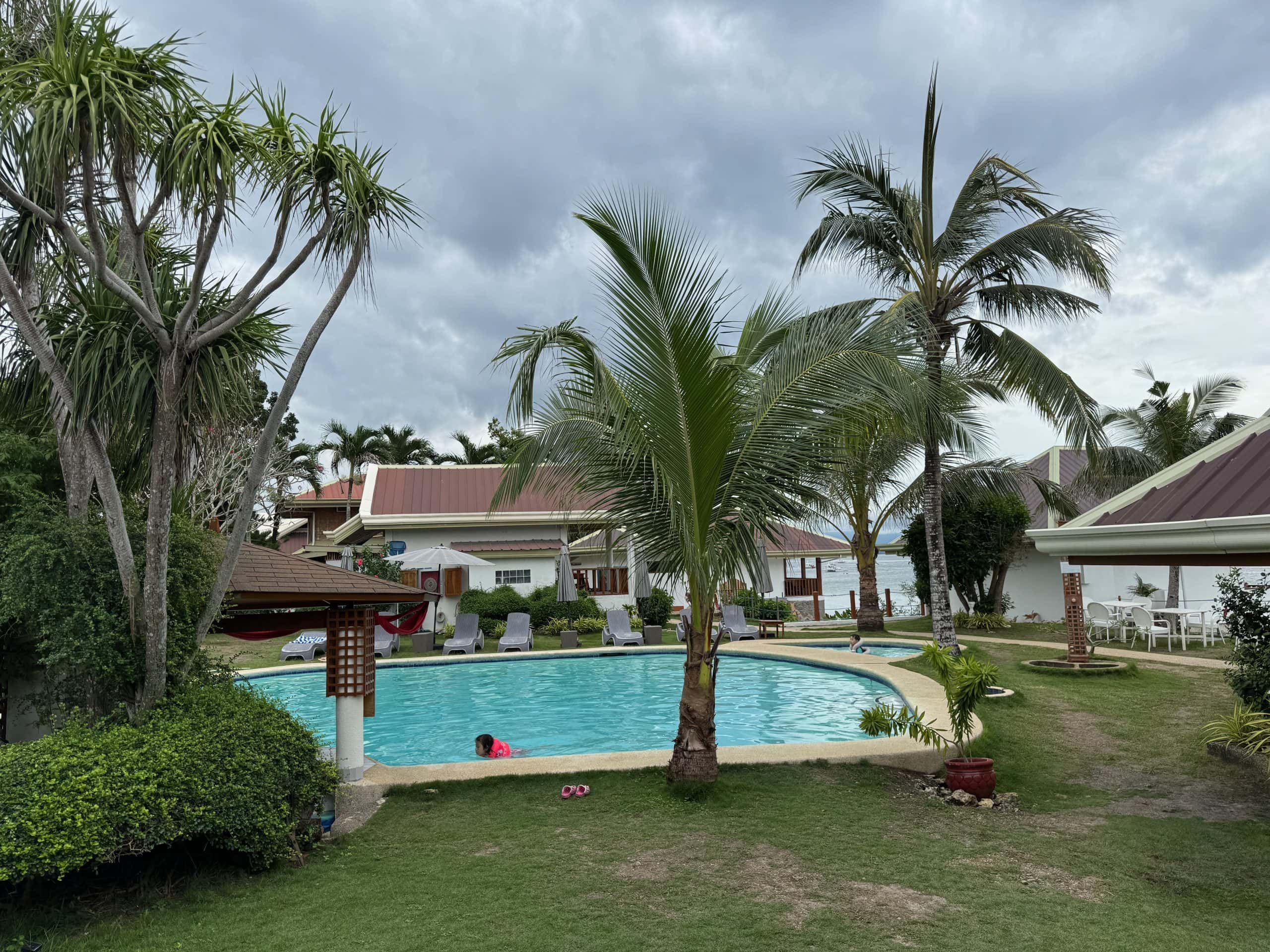 Pool and tropical garden area at Quo Vadis Dive Resort in Moalboal, Cebu, Philippines, a popular stay near Panagsama Beach known for diving access, waterfront views, and walkable nightlife.