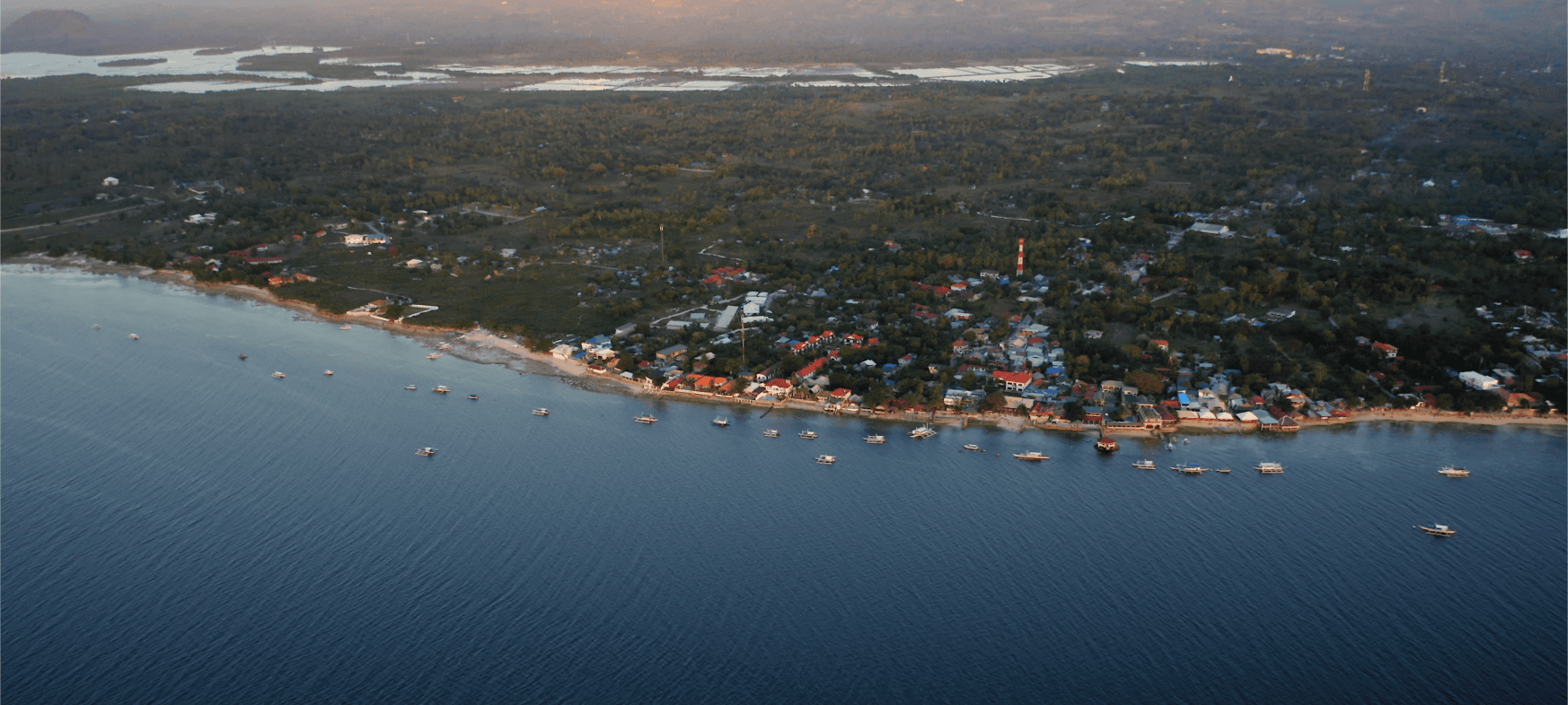 Drone view of Moalboal, Cebu, Philippines, showing the coastline near Panagsama Beach with traditional banca boats, tropical scenery, and one of the country’s top diving and sardine run destinations.