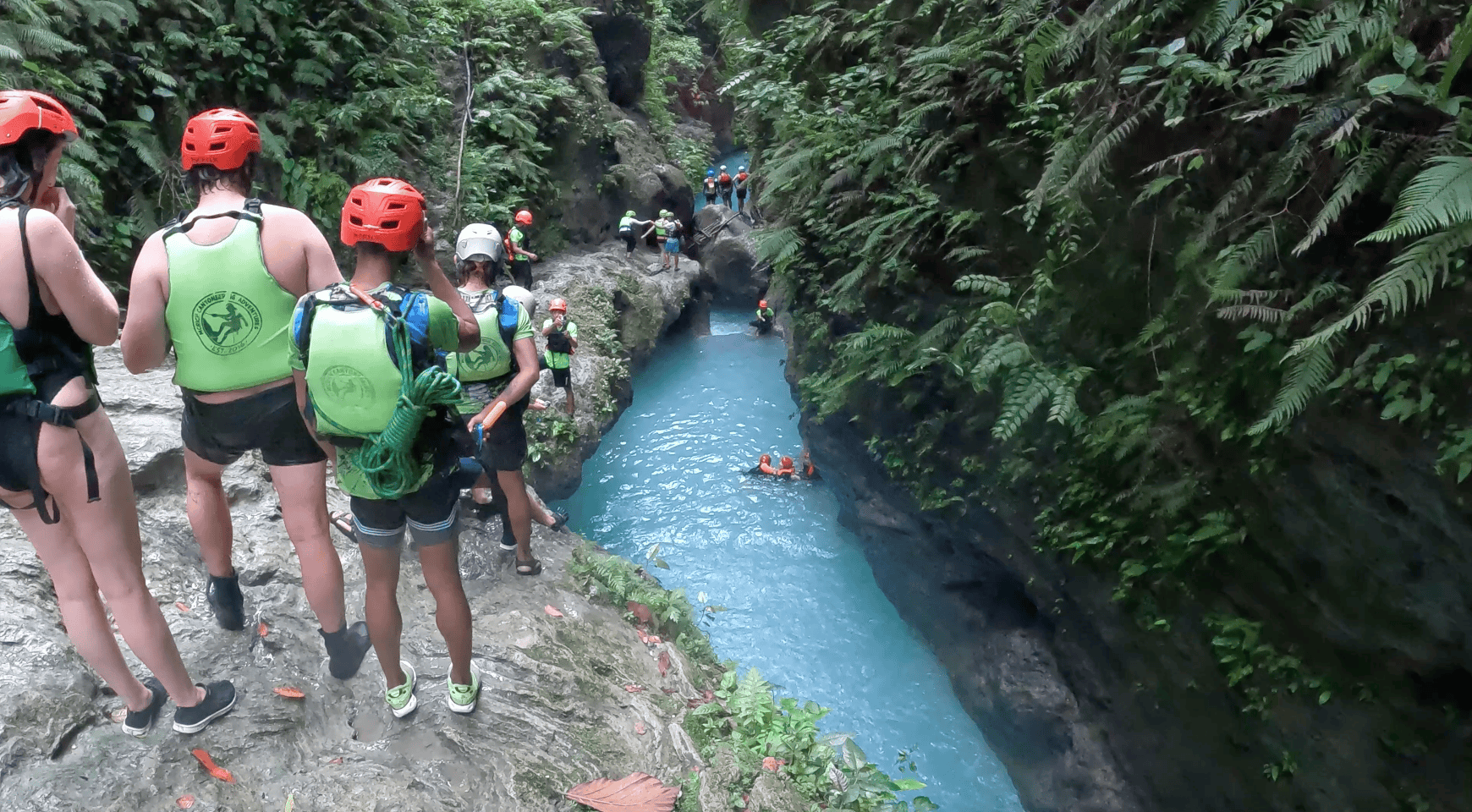 People canyoning through the turquoise river at Kawasan Falls near Moalboal, Cebu, Philippines, one of the most popular adventure day trips in the area known for cliff jumps, jungle canyons, and waterfalls.