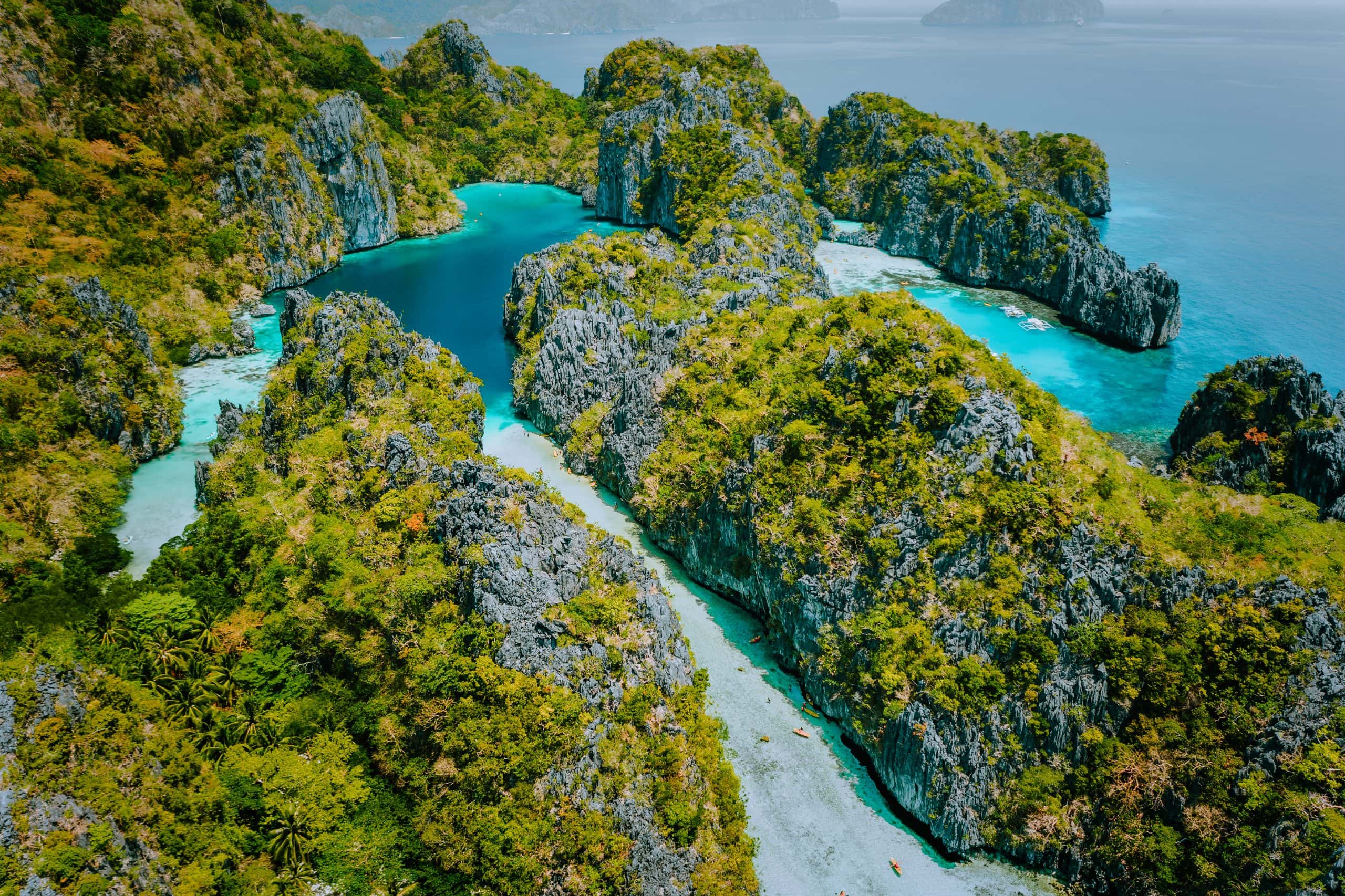Aerial drone view beautiful shallow tropical Big and Small Lagoon explored inside by tourist on kayaks surrounded by jagged limestone karst cliffs. El Nido, Palawan Philippines.