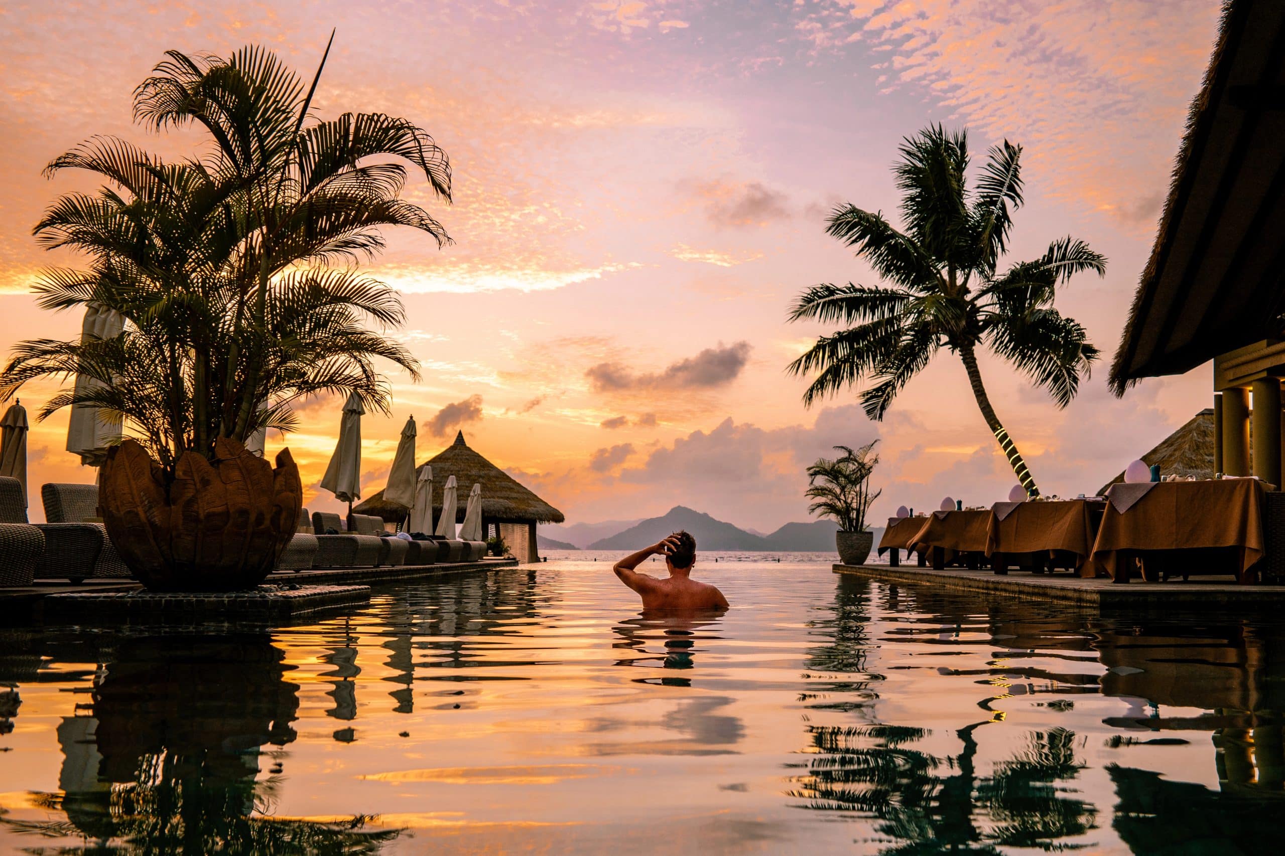 Luxury infinity pool overlooking a tropical island at sunset