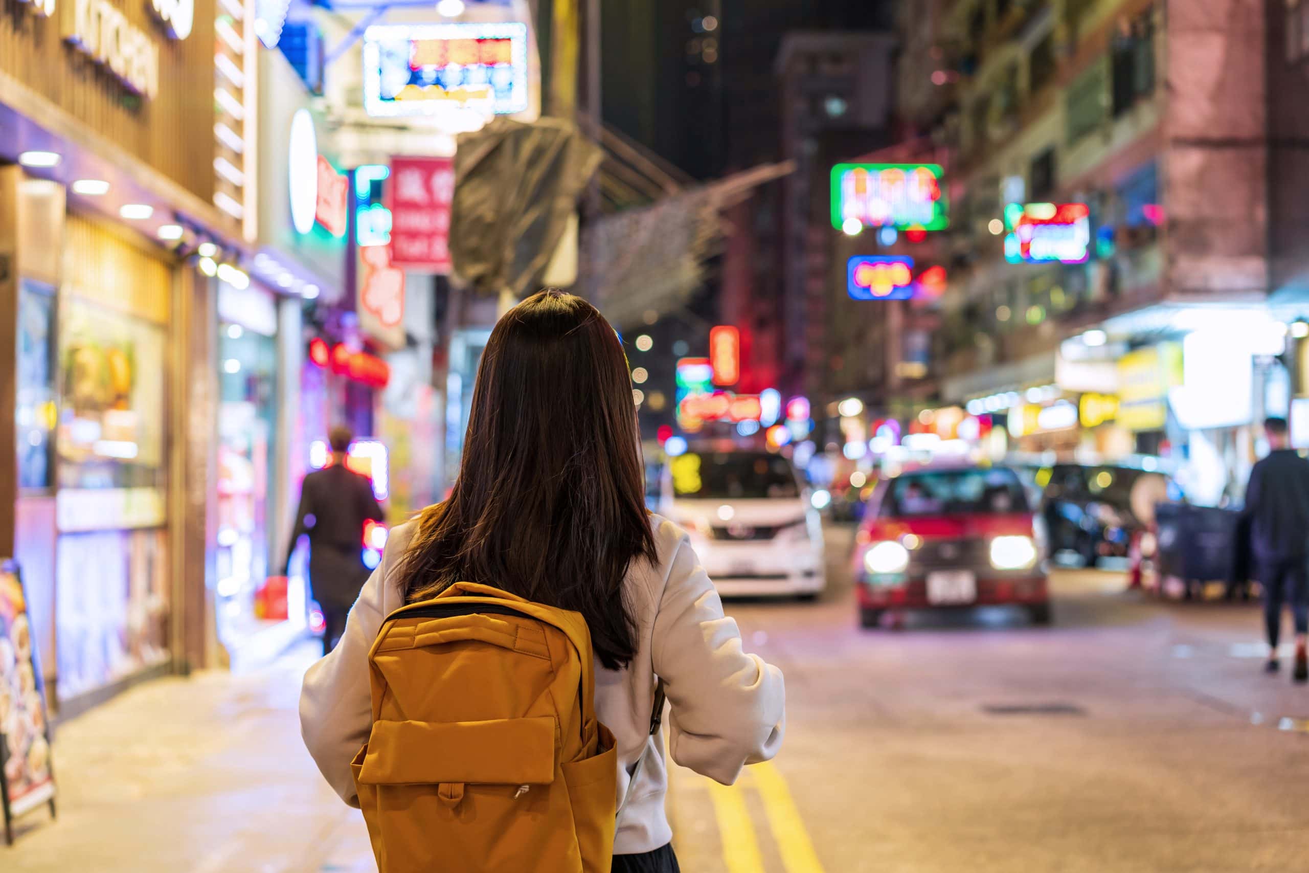 Backpacker exploring a busy night market in Hong Kong