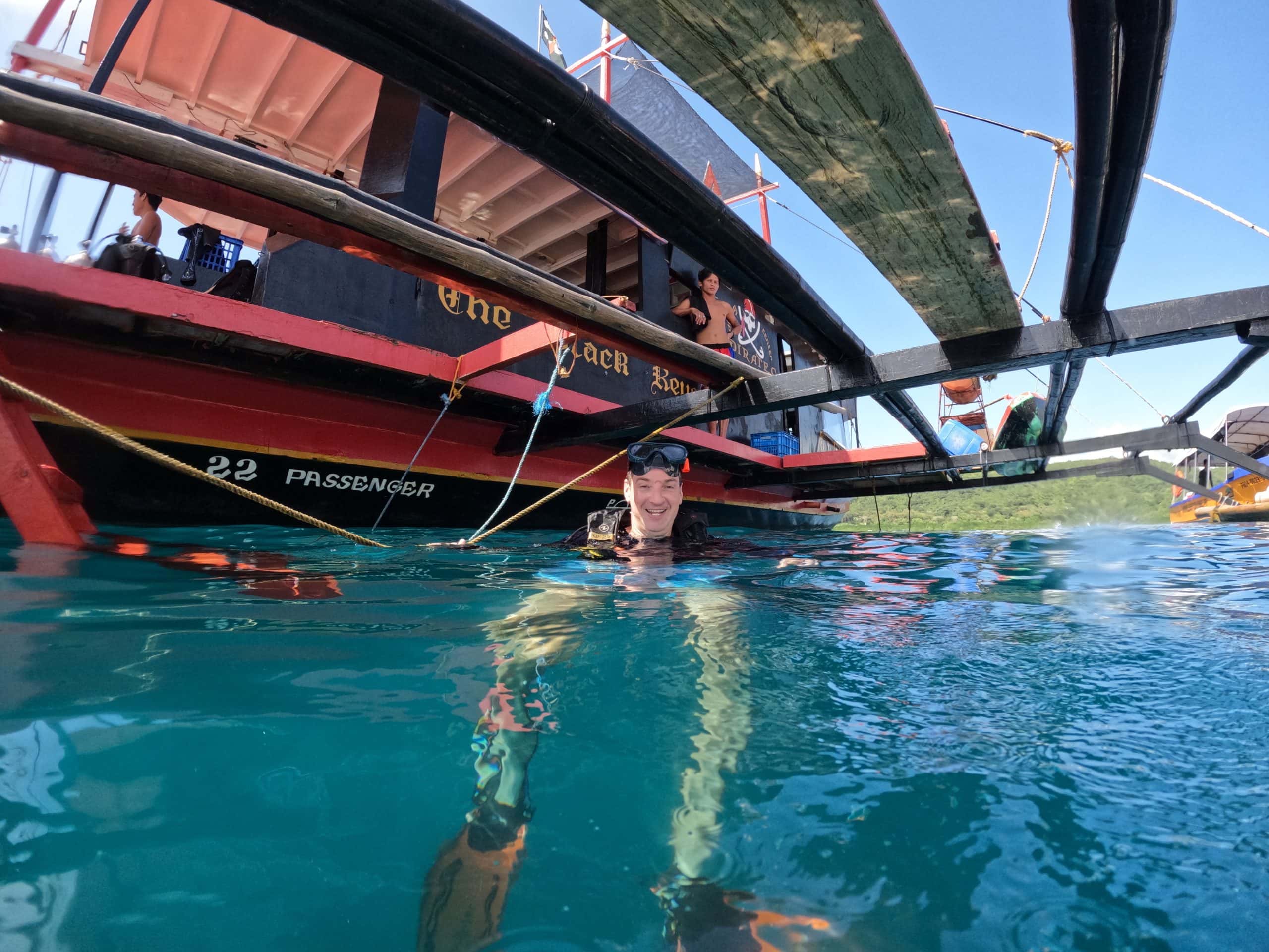Scuba diving from a traditional dive boat in Coron, Palawan, known for its accessible World War II shipwrecks and excellent wreck diving.