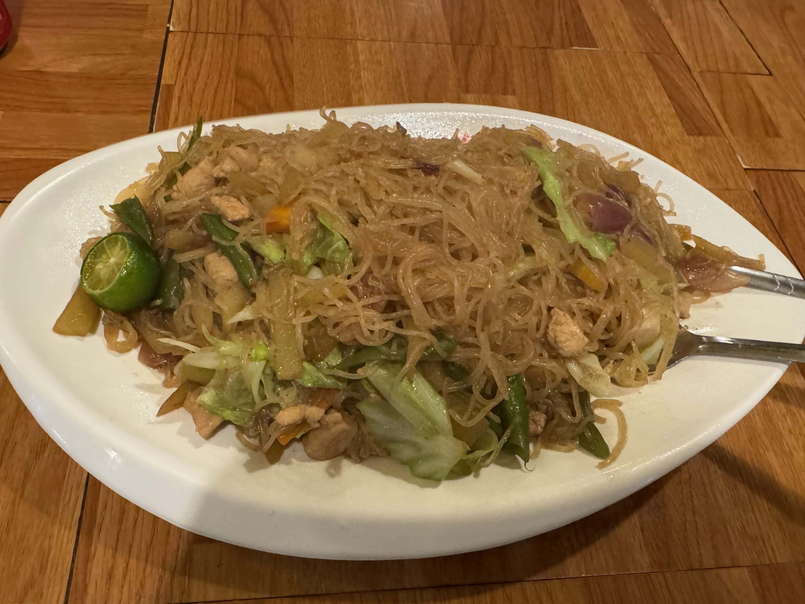 Traditional Filipino pancit bihon with rice noodles, chicken, vegetables and calamansi