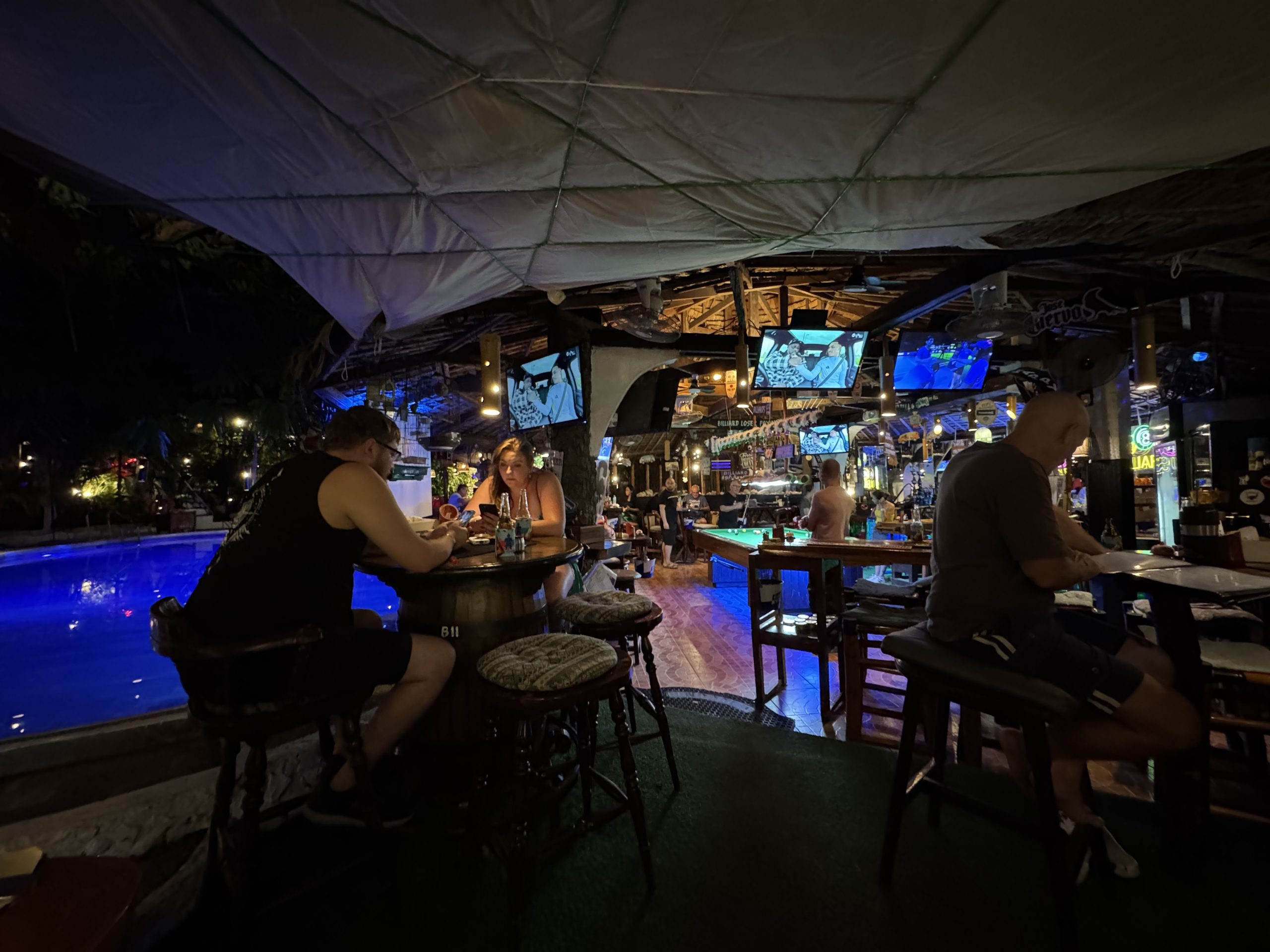 Nightlife in Puerto Galera, Mindoro, with a lively open-air bar, pool tables and visitors enjoying an evening out.