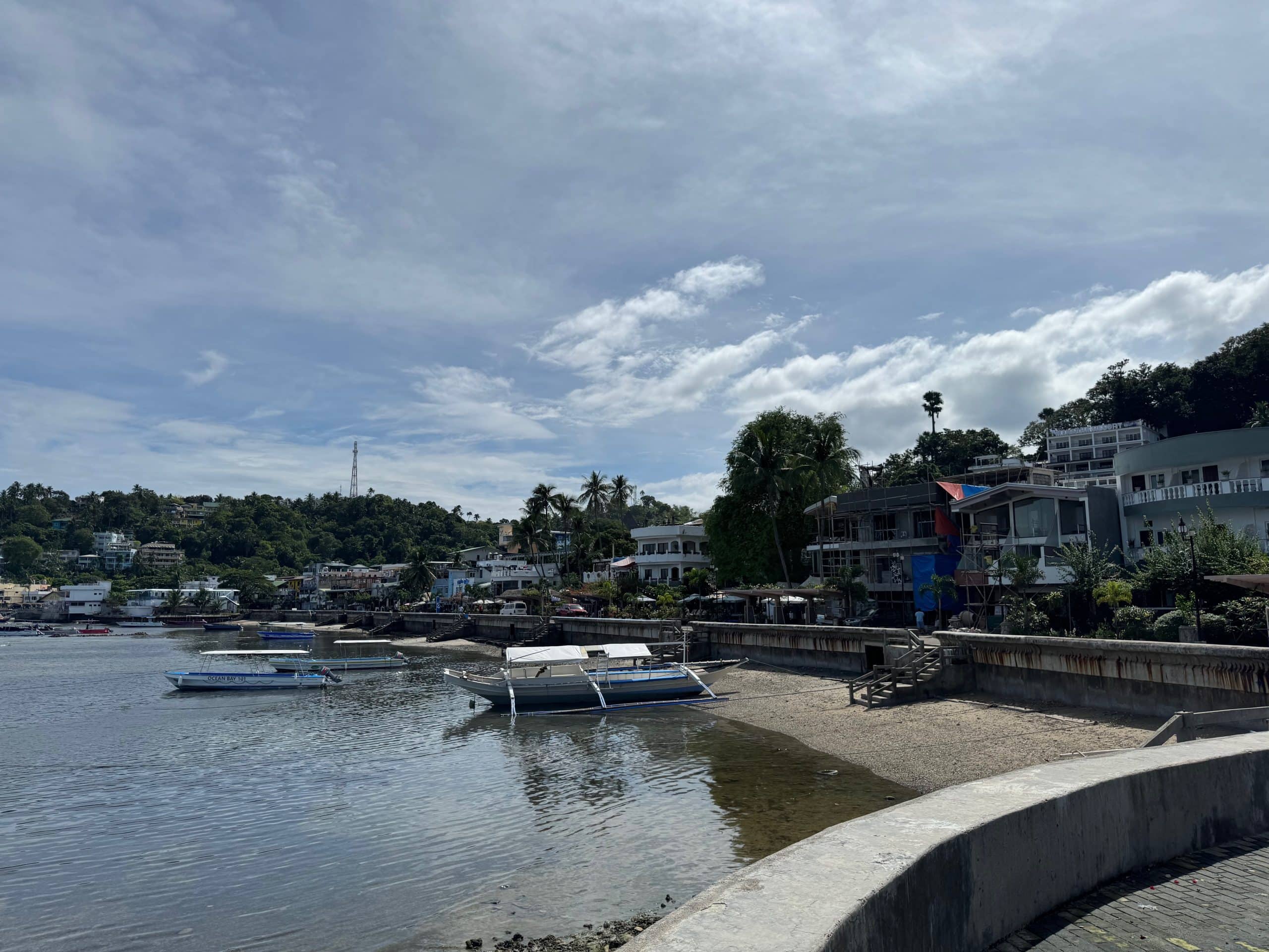 Sabang: Sabang in Puerto Galera, Mindoro, with traditional outrigger boats along the waterfront and hotels lining the bay.