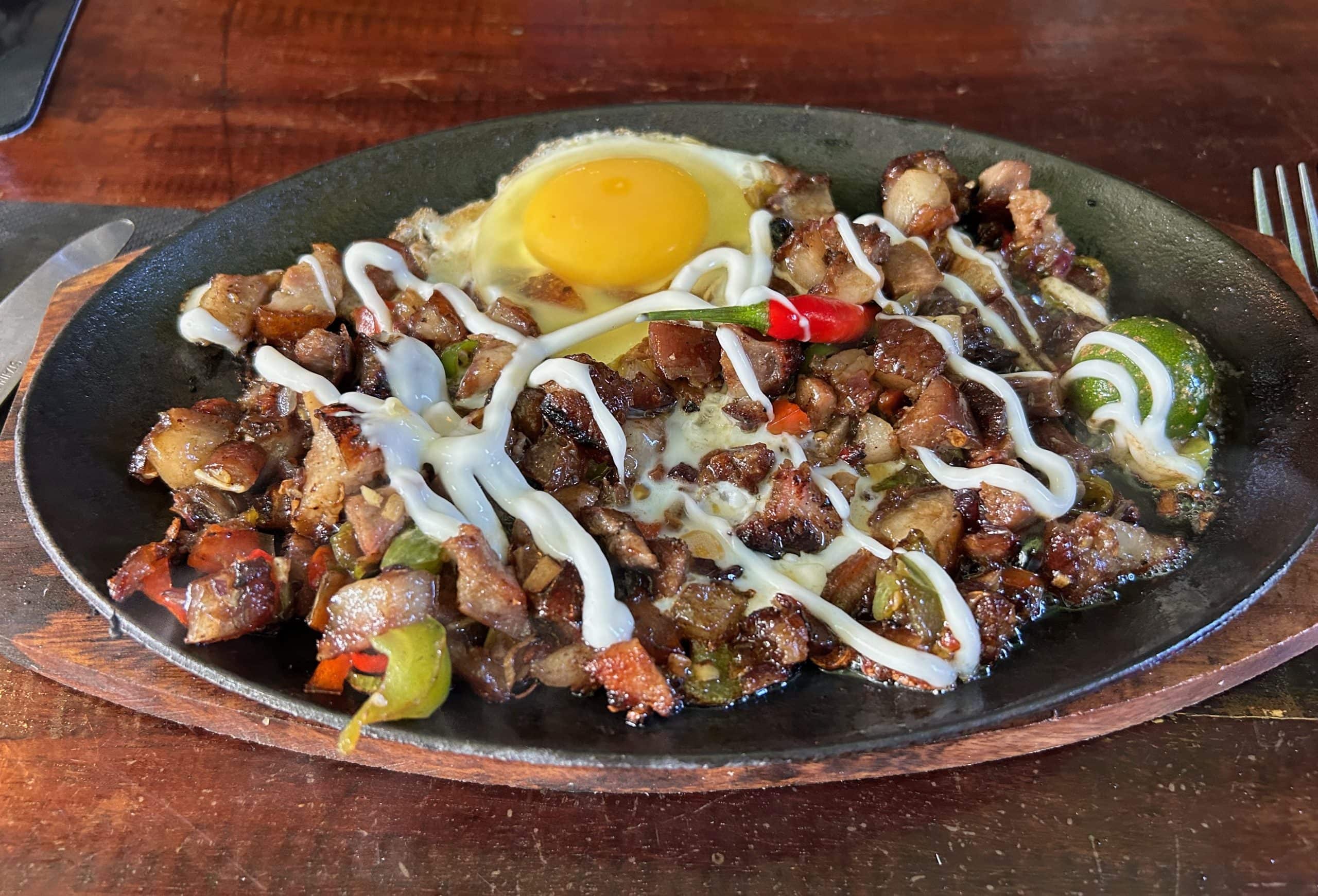 Filipino sisig served sizzling with pork, egg, chillies and calamansi.