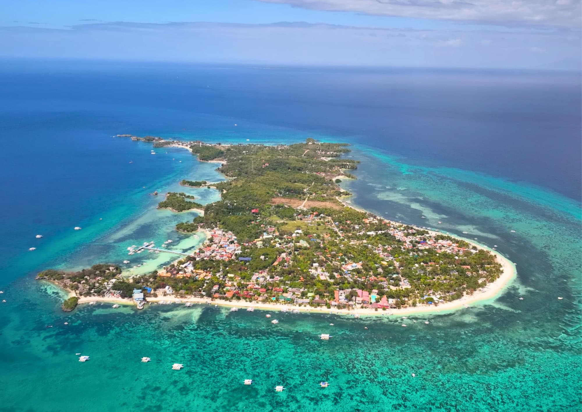 Aerial view of Malapascua Island surrounded by turquoise water and coral reefs in Cebu, Philippines.