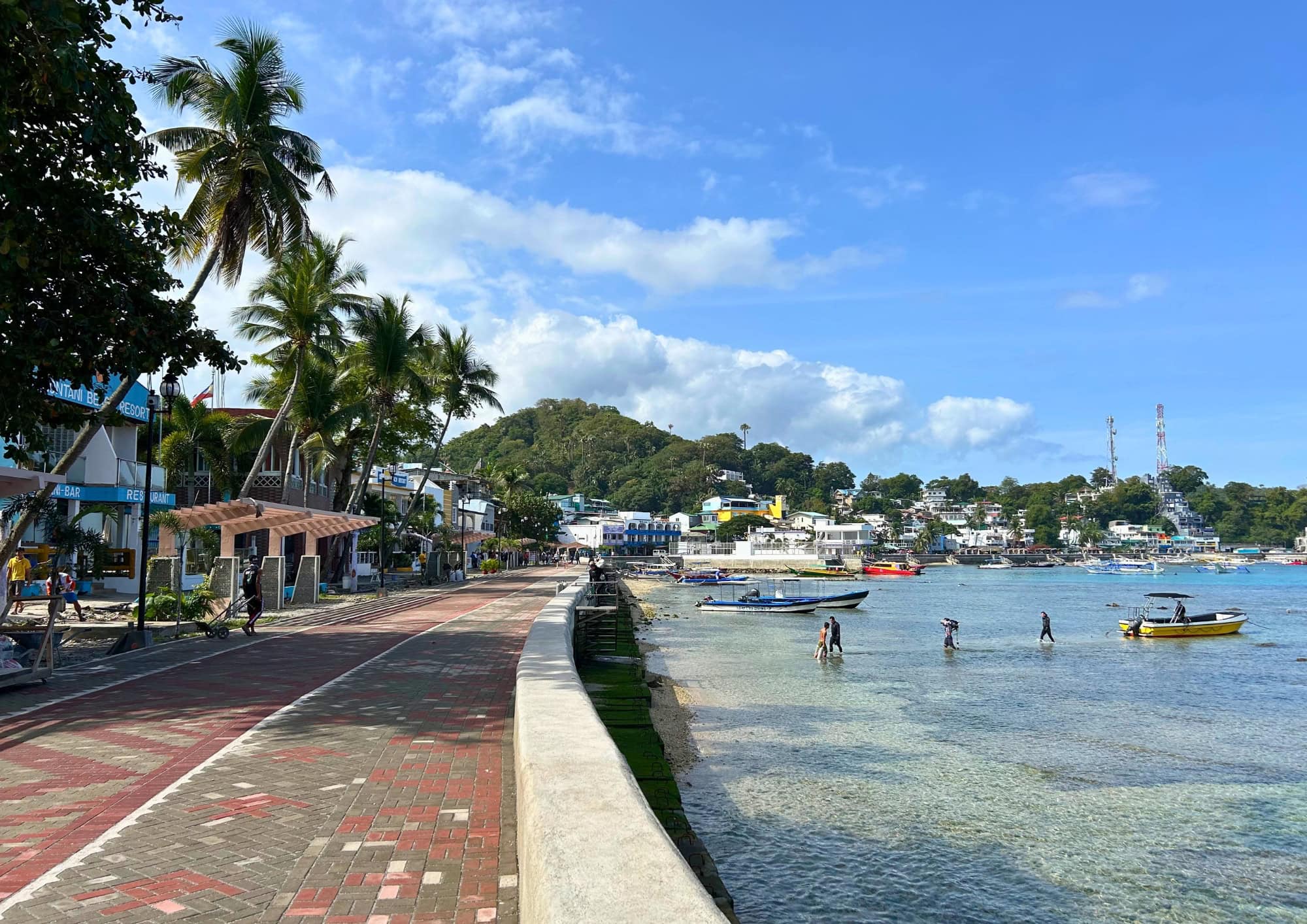 Waterfront promenade lined with palm trees overlooking Puerto Galera Bay.