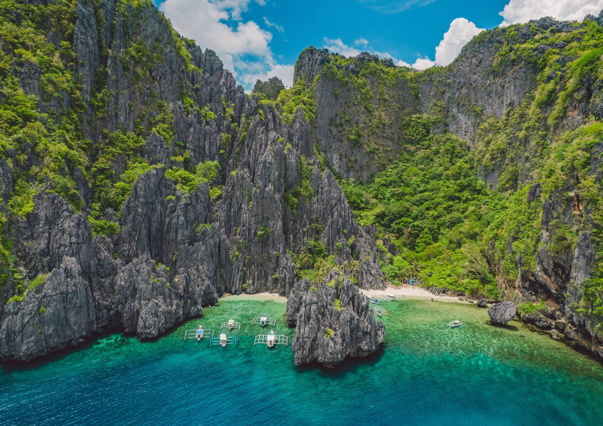 Hidden beach surrounded by towering limestone cliffs in El Nido, Palawan.