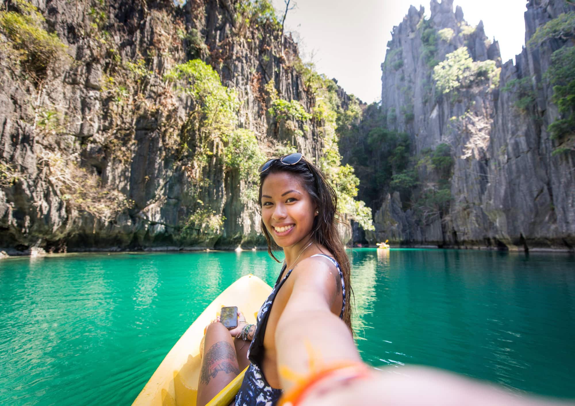 Traveller kayaking through the turquoise lagoons of Coron surrounded by towering limestone cliffs.